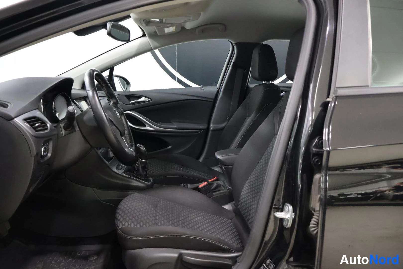 Etuistuimet: Interior cabin view showing driver's seat, front passenger seat and steering wheel with Opel logo, dashboard vents and door trim details visible.