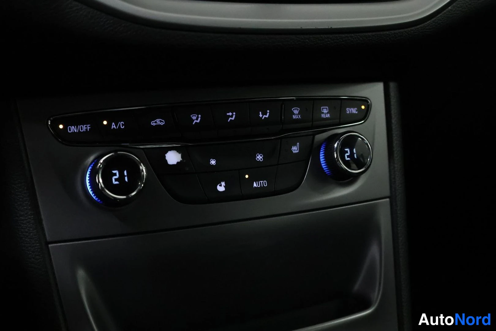 Muu: Interior close-up of the center console climate control panel with dual-zone automatic temperature settings displayed on digital dials set to 21 degrees Celsius