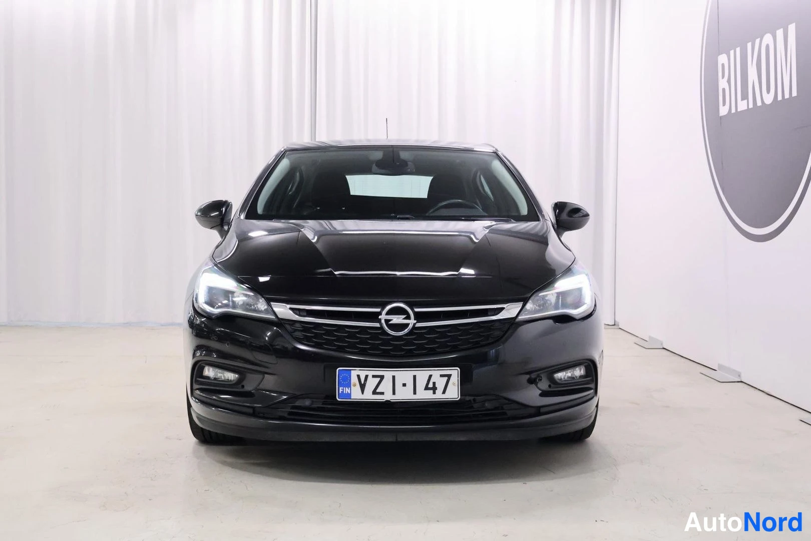 Edestä: Mustan Opel Astra -auton etunäkymä suoraan edestä, rekisteritunnus