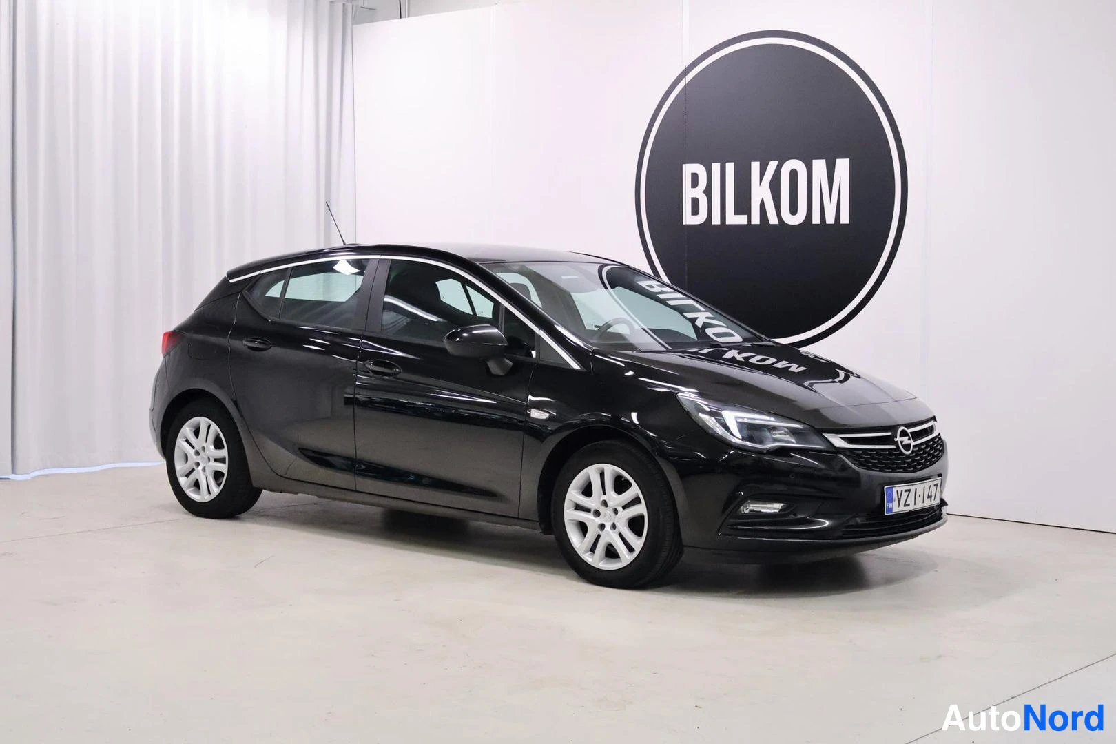 Etuviisto, nokka oikealle: Mustan Opel Astra -farmarin etukulma oikealta, rekisteri.
