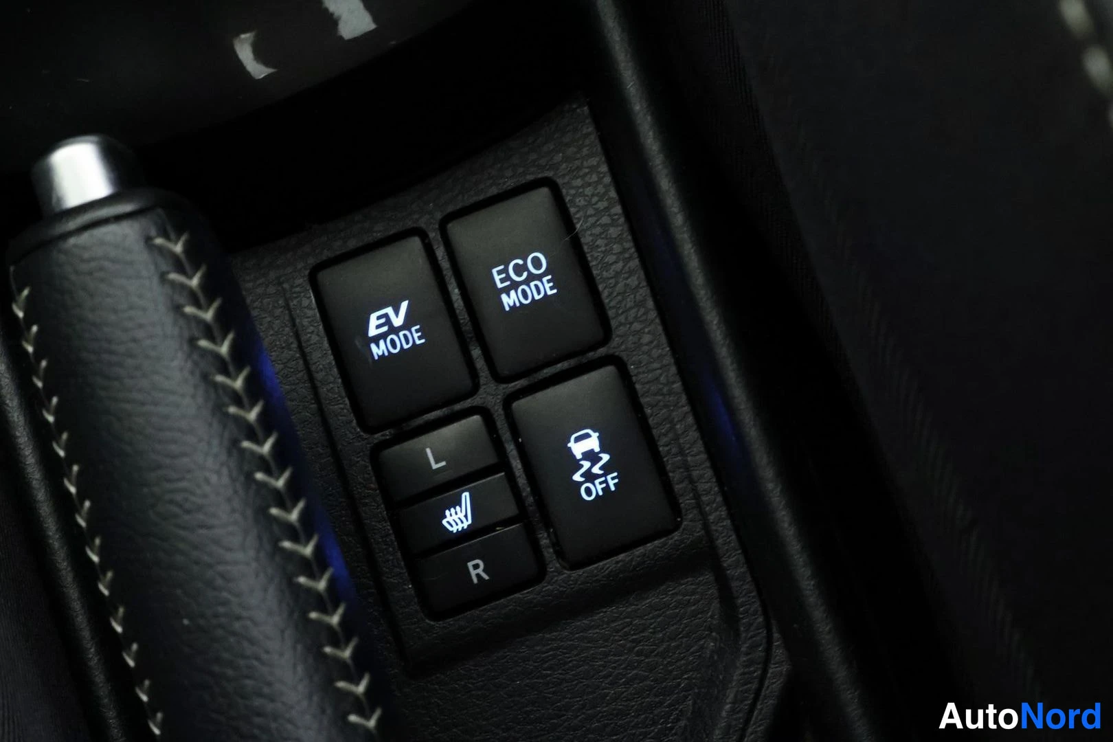 Yksityiskohta: Control buttons located in the center console next to a gear selector: 'EV MODE', 'ECO MODE', traction control 'OFF', and a heated steering wheel switch labeled