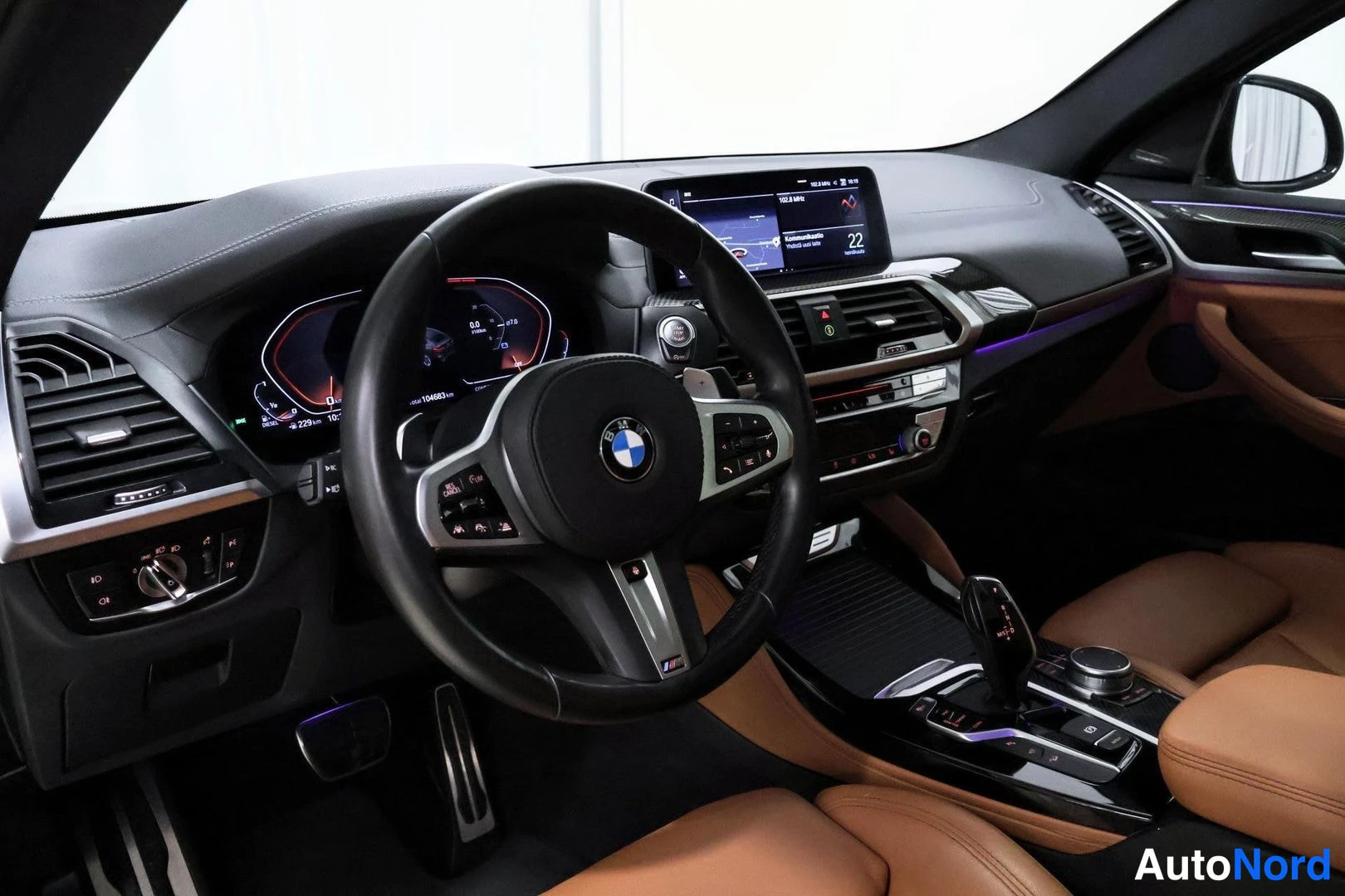 Muu: Ohjaamon näkymä: BMW-ohjauspyörä, digitaalinen mittaristo, keskinäytöllä kartta ja neste­näyttö sekä beige­nahkaiset etuistuimet.