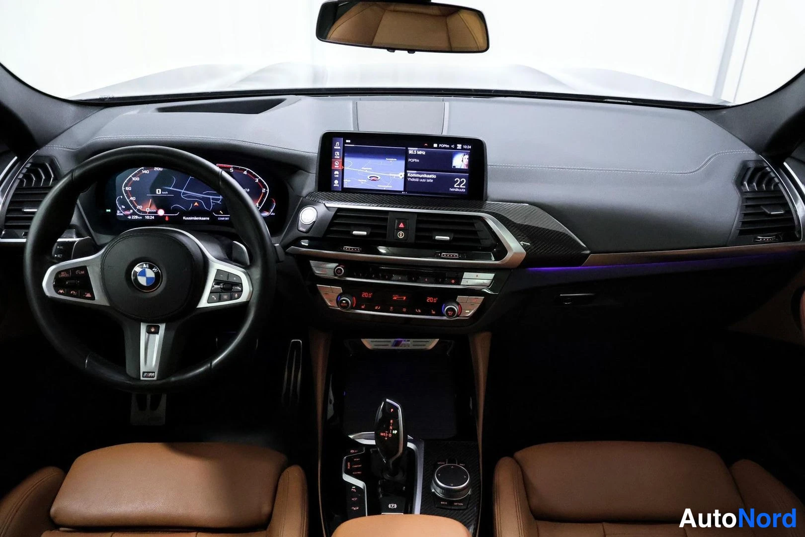 Muu: Näkymä ohjaamoon: BMW-ohjauspyörä, digitaalinen mittaristo, kartta­navigaationäyttö ja ruskeat nahkaistuimet.