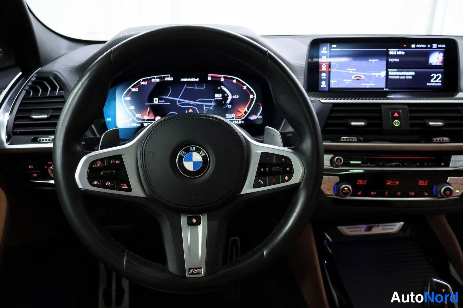 Muu: Lähikuva BMW-ohjauspyörästä ja digitaalisesta mittaristosta, taustalla keskikonsolin näyttö.