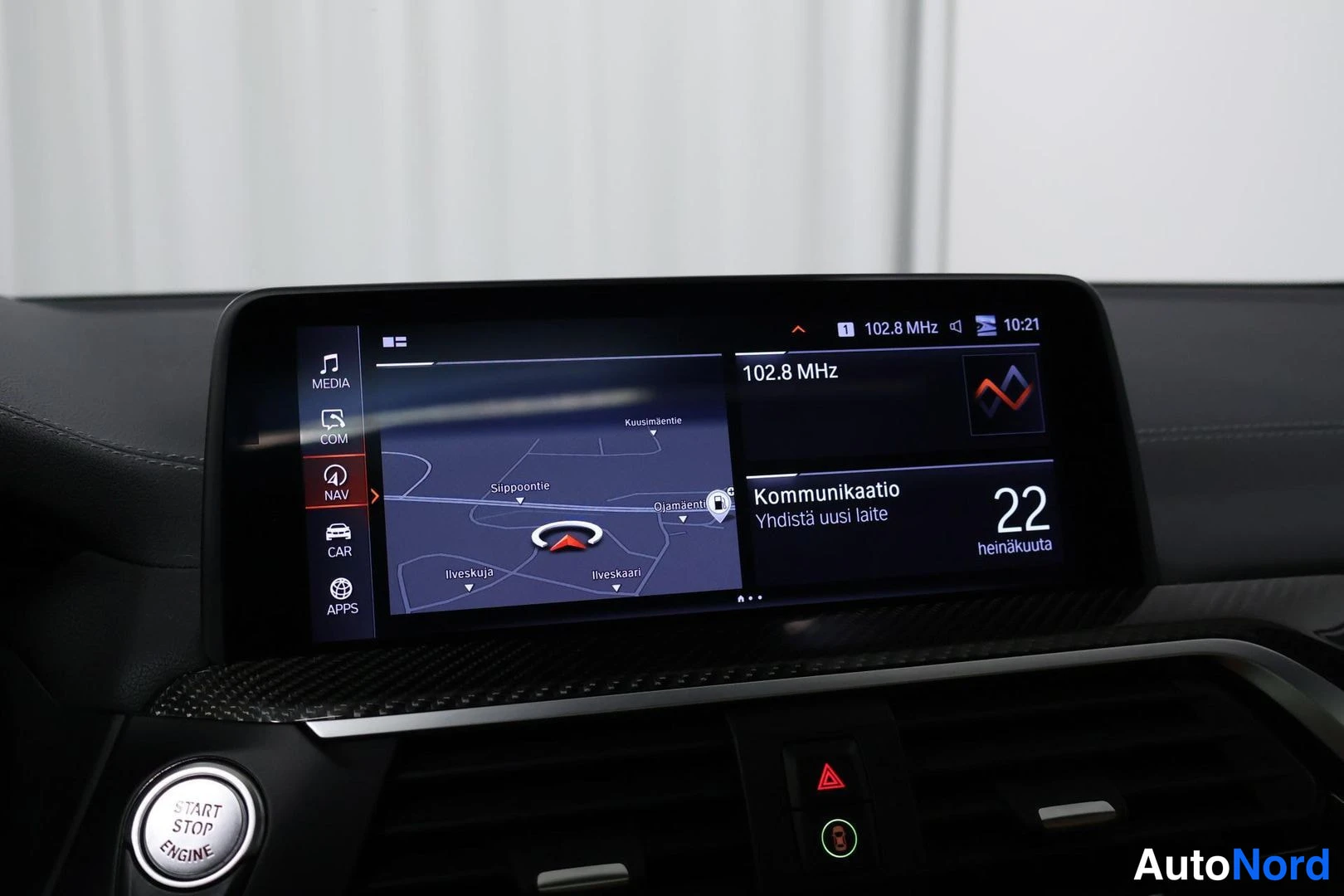 Yksityiskohta: Keskinäyttö näyttää navigointikartan (Kuusimäentie, Ilveskujan alue) sekä 102,8 MHz radioaseman; näytön valikossa MEDIA, COM, NAV, CAR ja APPS, alla START STOP