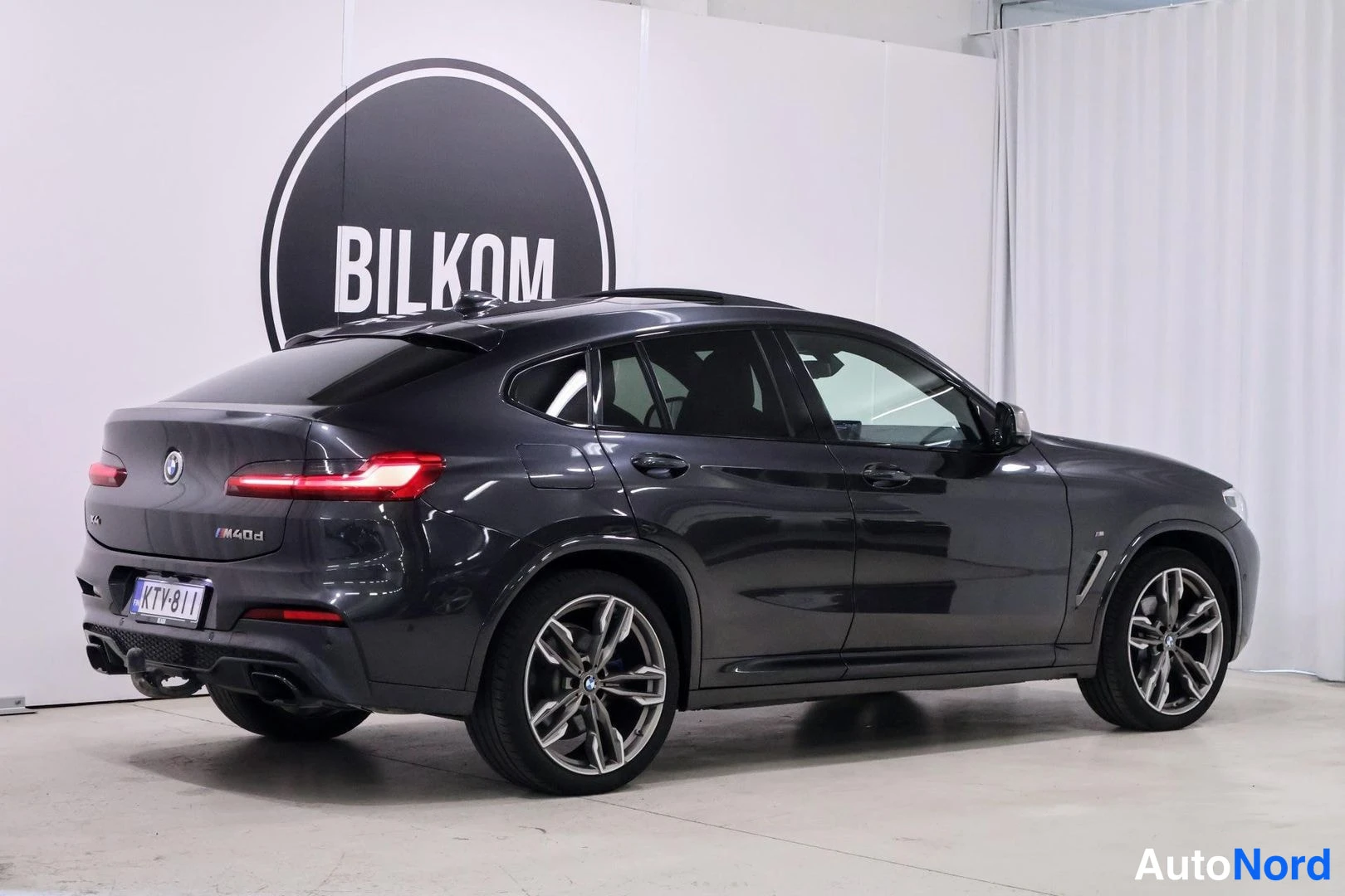 Takaviisto: Auton takaosa ja vasen kylki näkyvissä; tummanharmaa BMW:llä M40d-tunnus ja rekisterikilpi, vetokoukku takapuskurin alla.