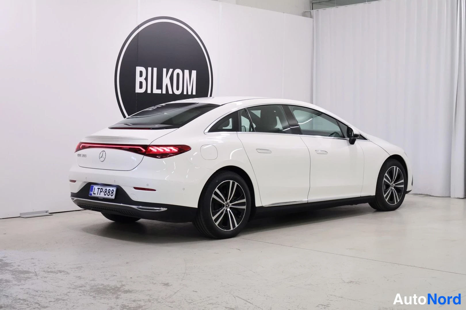Etuviisto, nokka oikealle: White sedan from the front three-quarter angle showing the side profile and wheel design