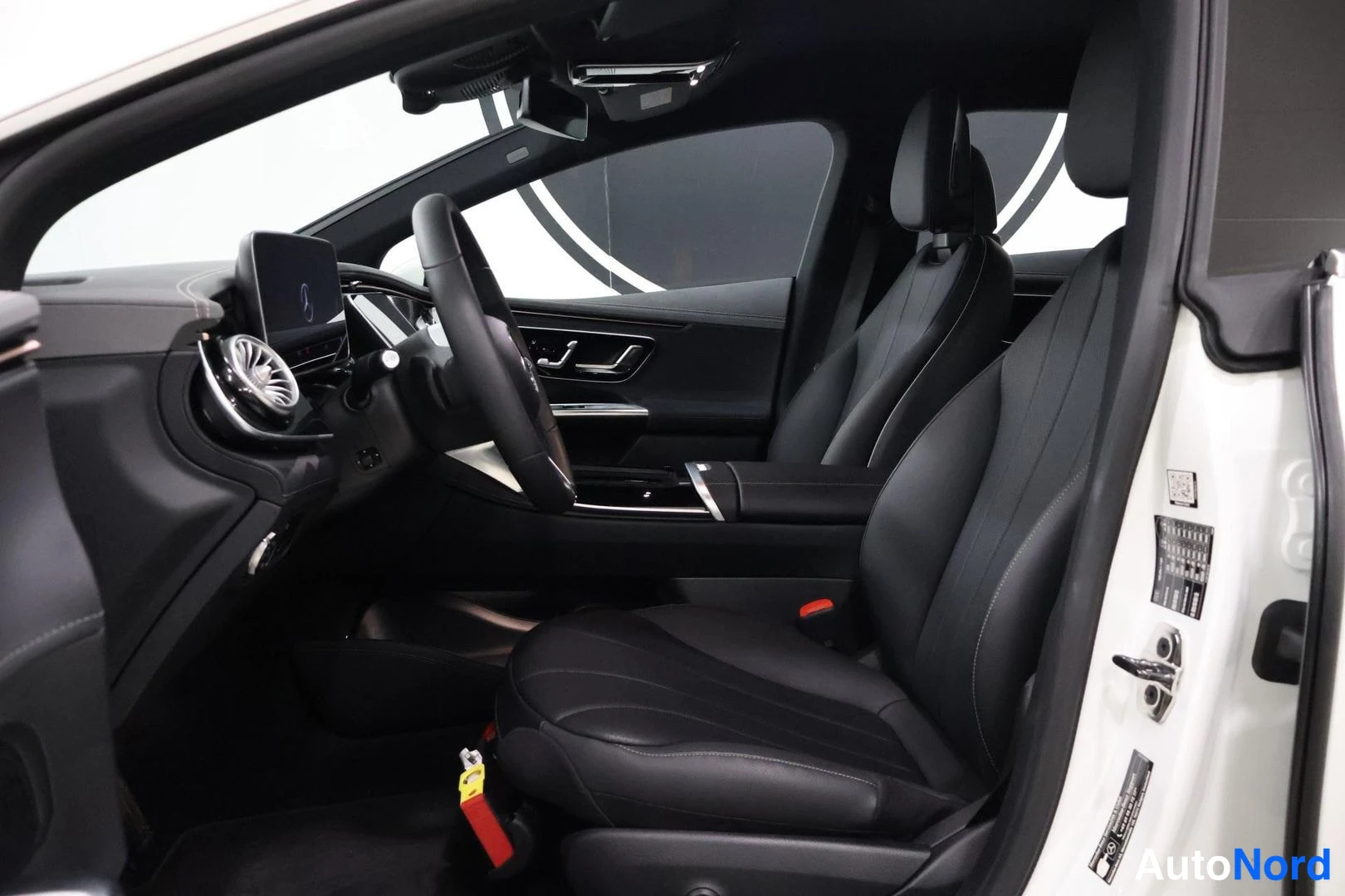 Ohjaamo: Interior shot of the driver's side featuring a black leather seat, steering wheel, and circular air vent