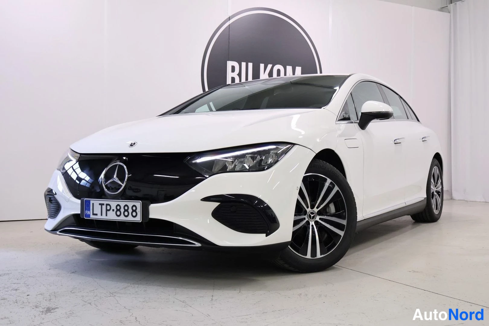 Etuviisto, nokka vasemmalle: Mercedes-Benz EQE -sedanin keula lähikulmassa vasemmalta, valkoinen korimalli, musta säleikkö, rekisteritunnus.