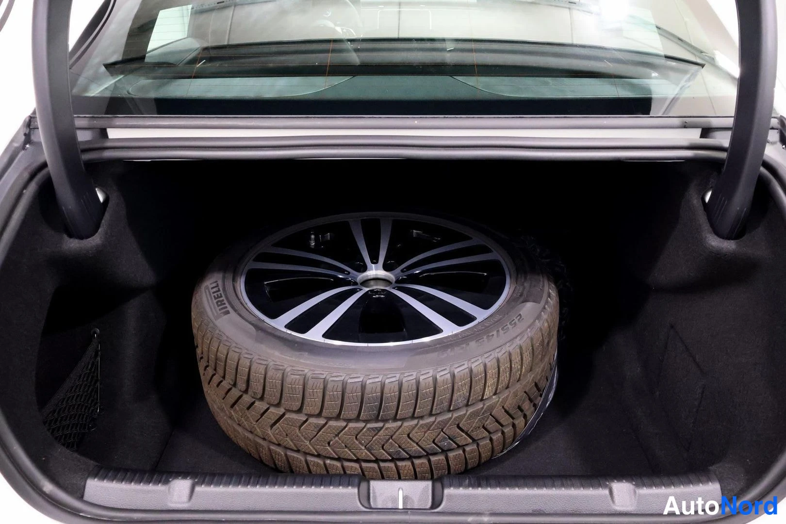 Muu: Auki avattu automaatin tavaratila, jonka pohjalla on varapyörä Pirelli-nastarenkaalla ja tumma alumiinivannenäkyvissä.