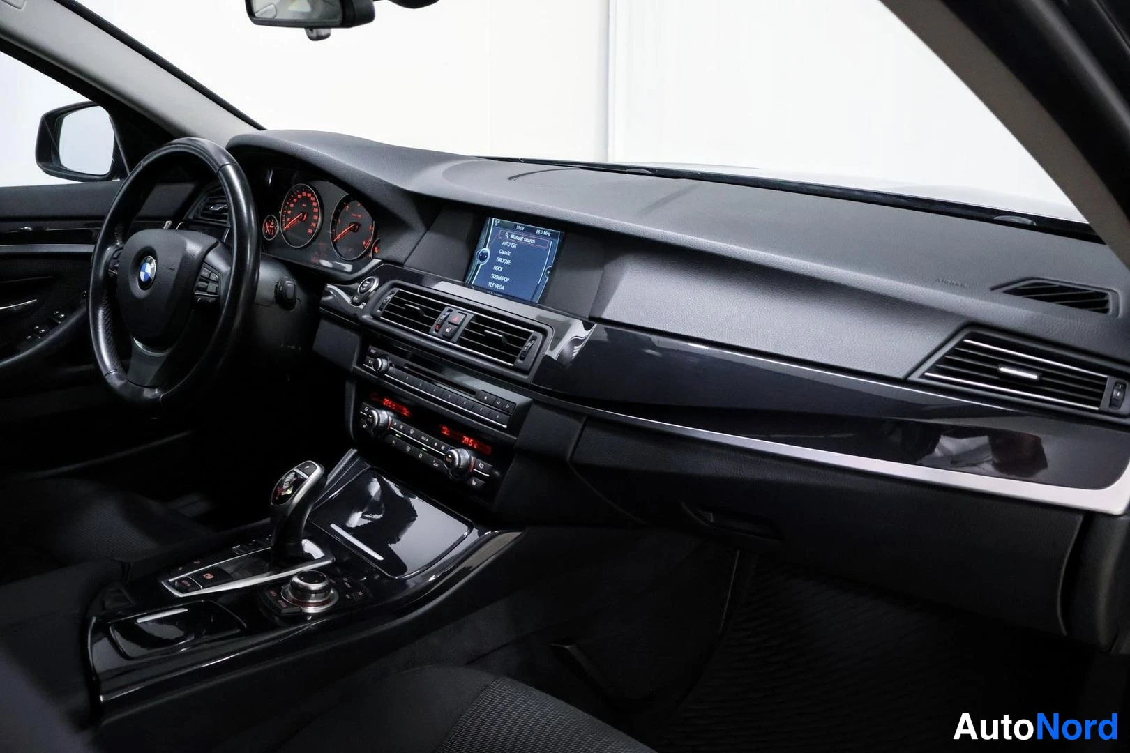 Etuistuimet: Passenger side dashboard perspective with center console and instrument cluster visible; visible equipment: climate control, navigation
