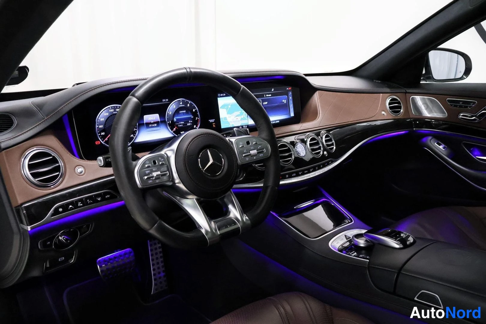 Muu: Ohjaamo näkyvissä: Mercedes-ohjauspyörä, digitaalinen mittaristo ja keskikonsolin infotainment-näyttö, ruskealla nahkapaneelilla koristeltu kojelauta ja sininen