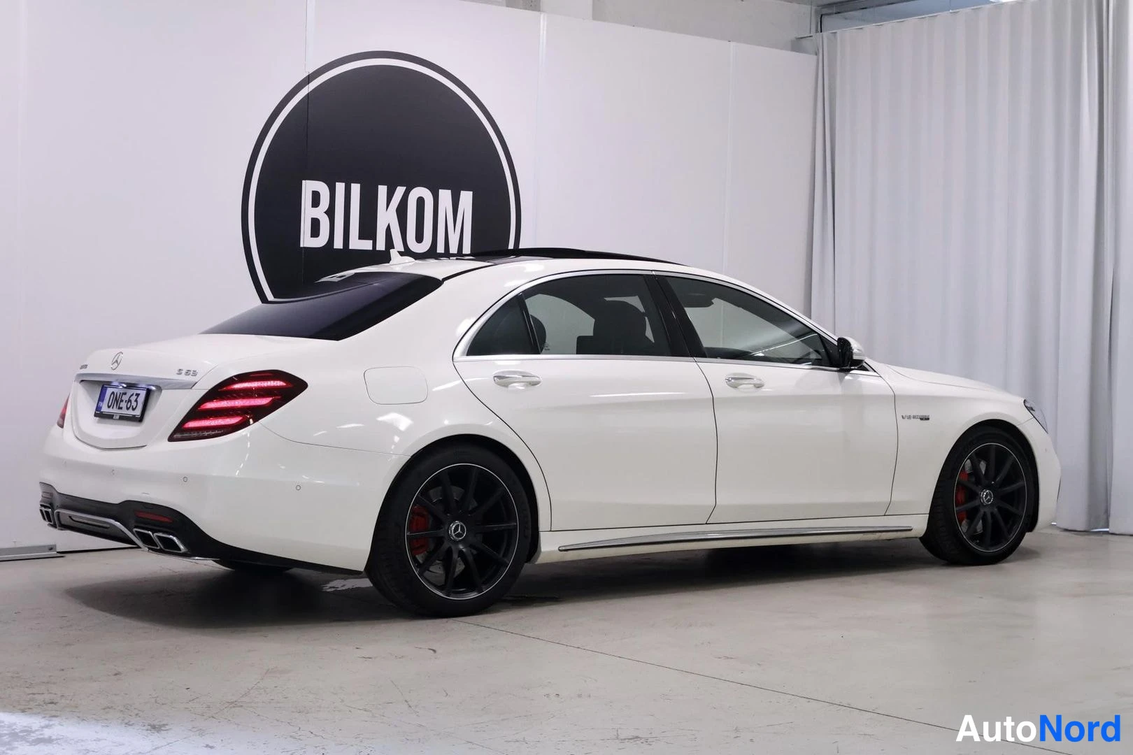 Takaviisto: Mercedes-Benz S 63, takakulma valkoinen sedan, mustat pultit ja punaiset jarrusatulat näkyvät