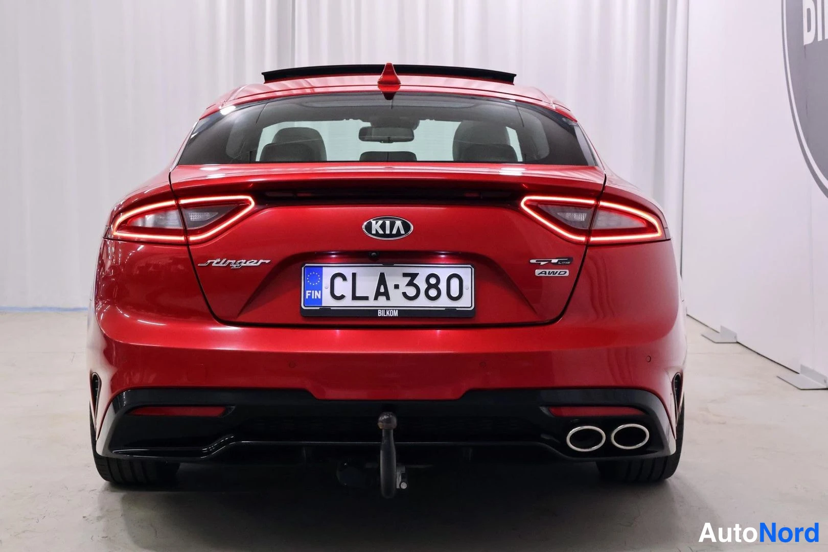 Takaa: Punaisen Kia Stinger -auton takaosa, kilpi, Stinger- ja GT AWD -merkinnät, kattoluukku ja vetokoulu.