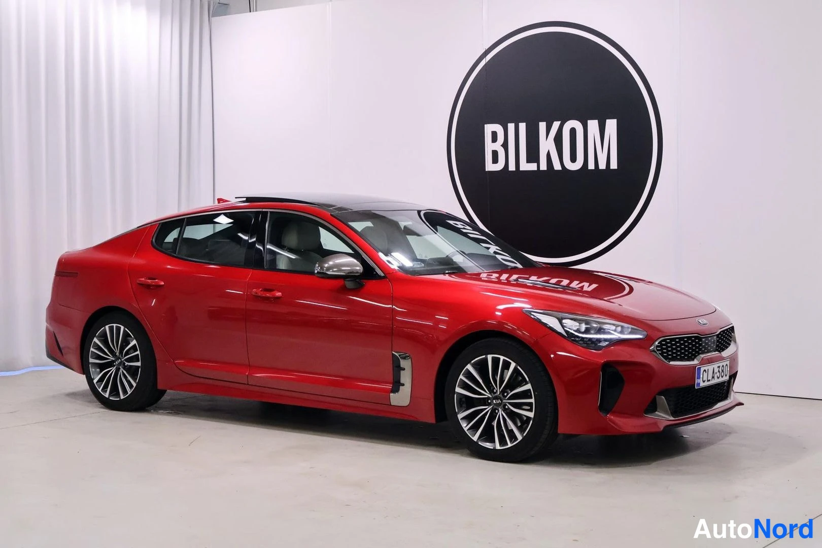 Etuviisto, nokka oikealle: Red Kia Stinger front three-quarter right profile with LED headlights on