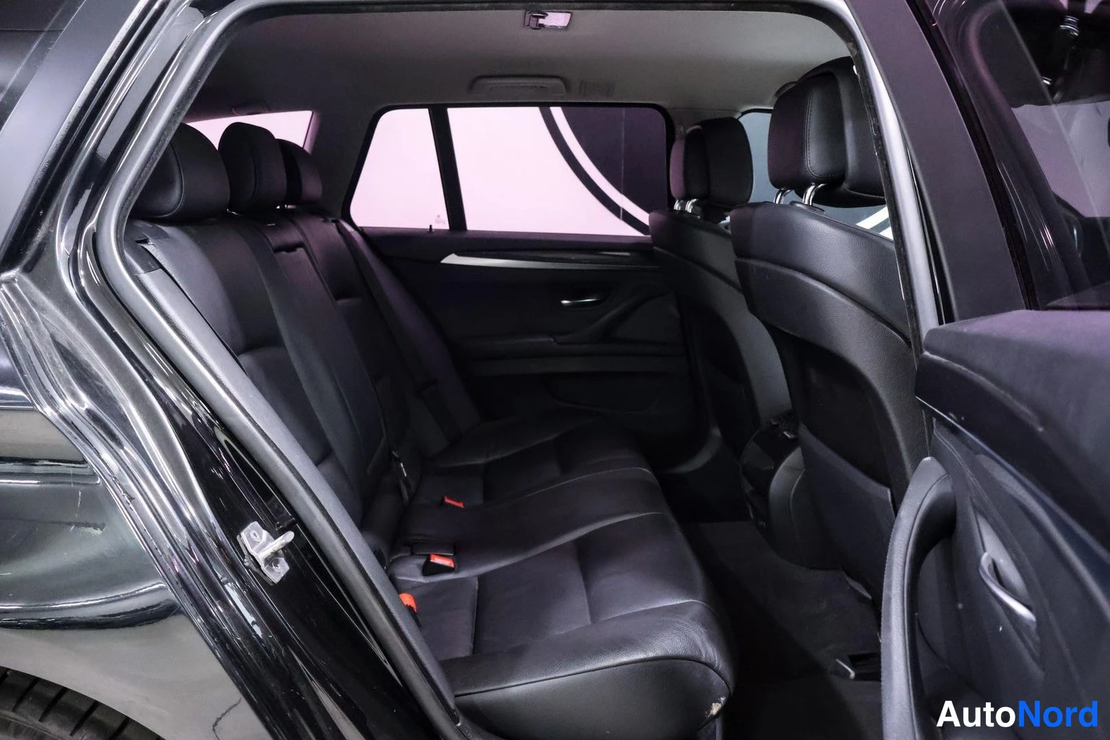Takaistuimet: View into the rear cabin showing black leather rear bench seats with headrests. The panoramic sunroof is visible on the ceiling above.