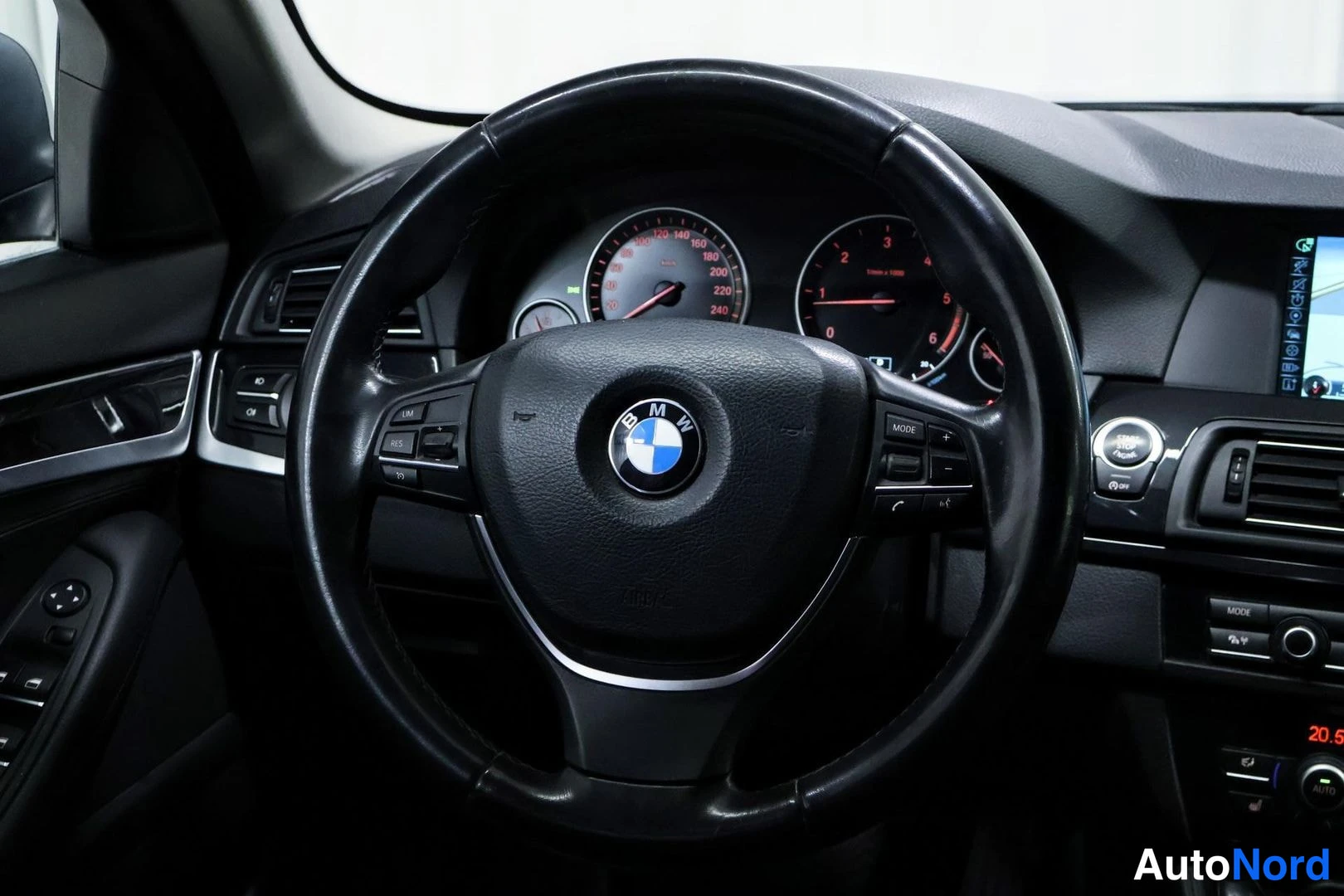 Etuviisto, nokka vasemmalle: Ohjauspyörä ja kojelauta BMW-merkillä, mittarit ja infotainmentnäyttö näkyvät.