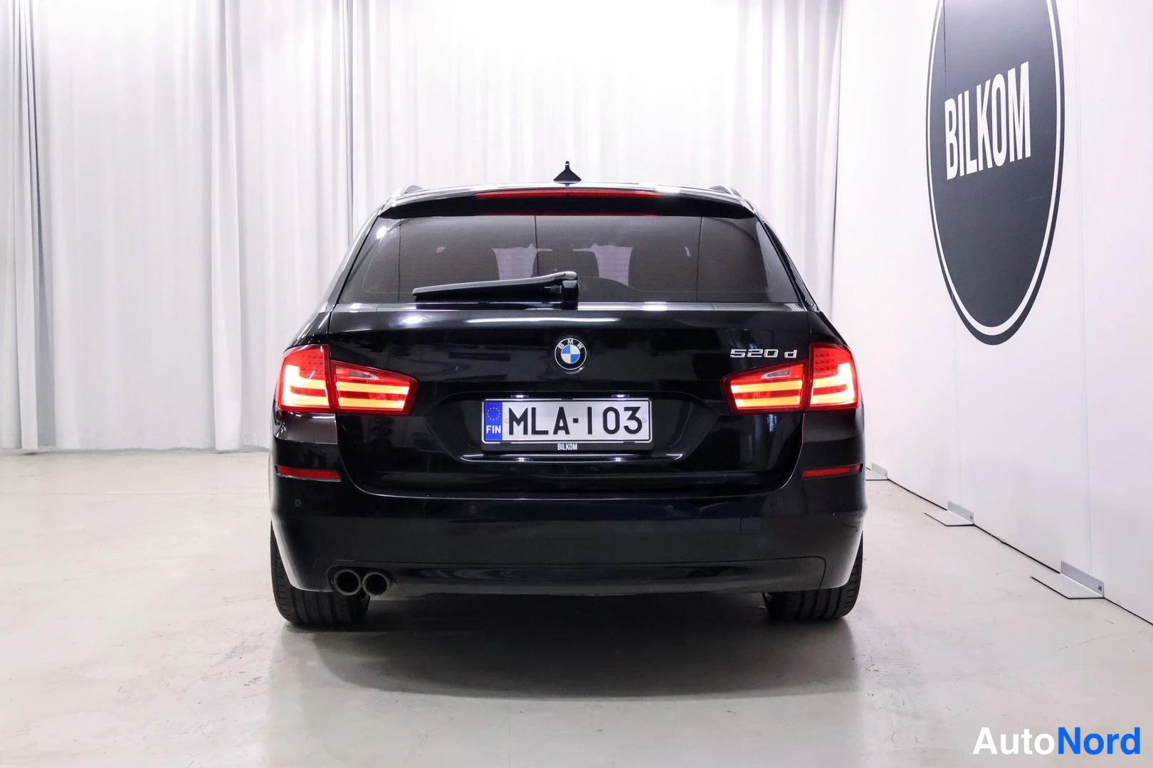 Takaa: Mustan farmariauton perä suoraan takaa kuvattuna; takaluukussa 520 d -teksti ja BMW-merkki, rekisteritunnus sekä kaksoispakoputket näkyvät.