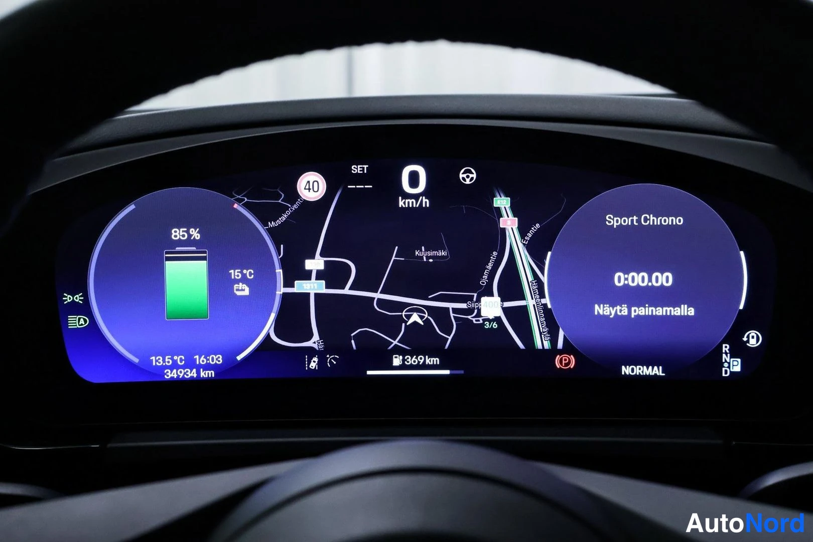 Yksityiskohta: Full view of the digital instrument cluster displaying driving information: map navigation, battery charge at 85%, temperature readings, 369 km range remaining,