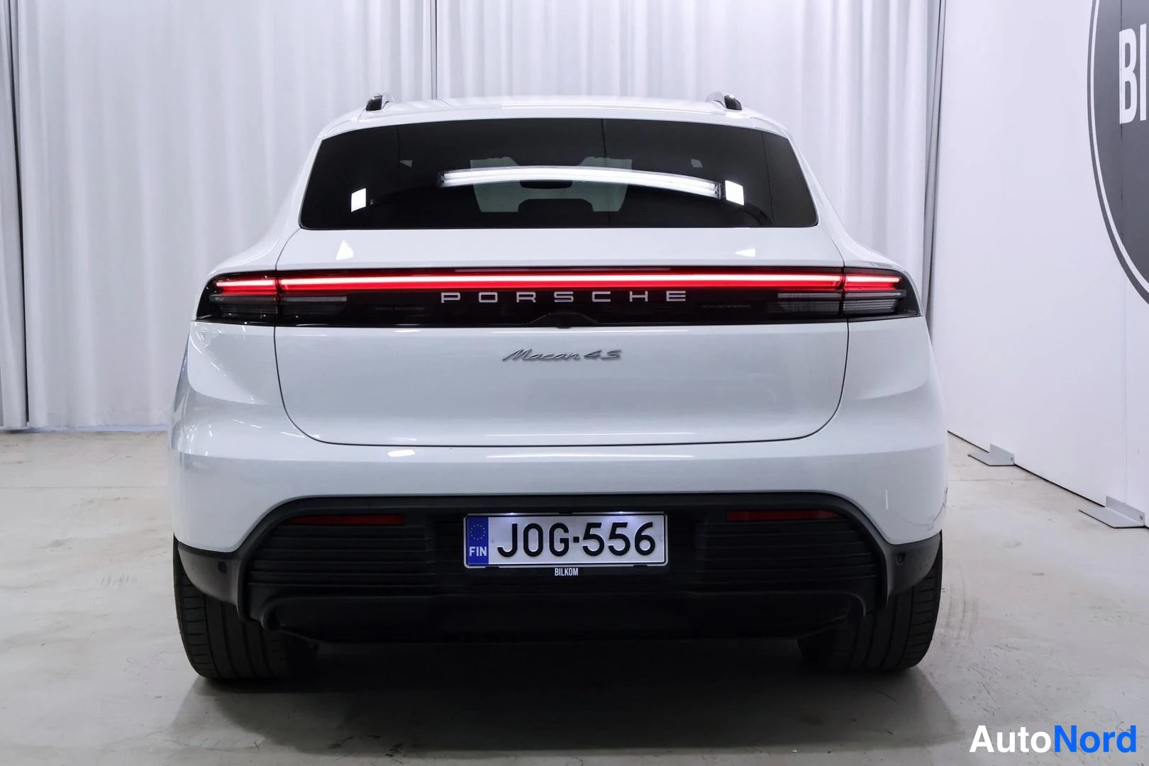 Takaa: Valkoinen Porsche Macan suoraan takaa kuvattuna, vaaleassa takapaneelissa PORSCHE-teksti ja mallimerkintä, rekisteritunnus.