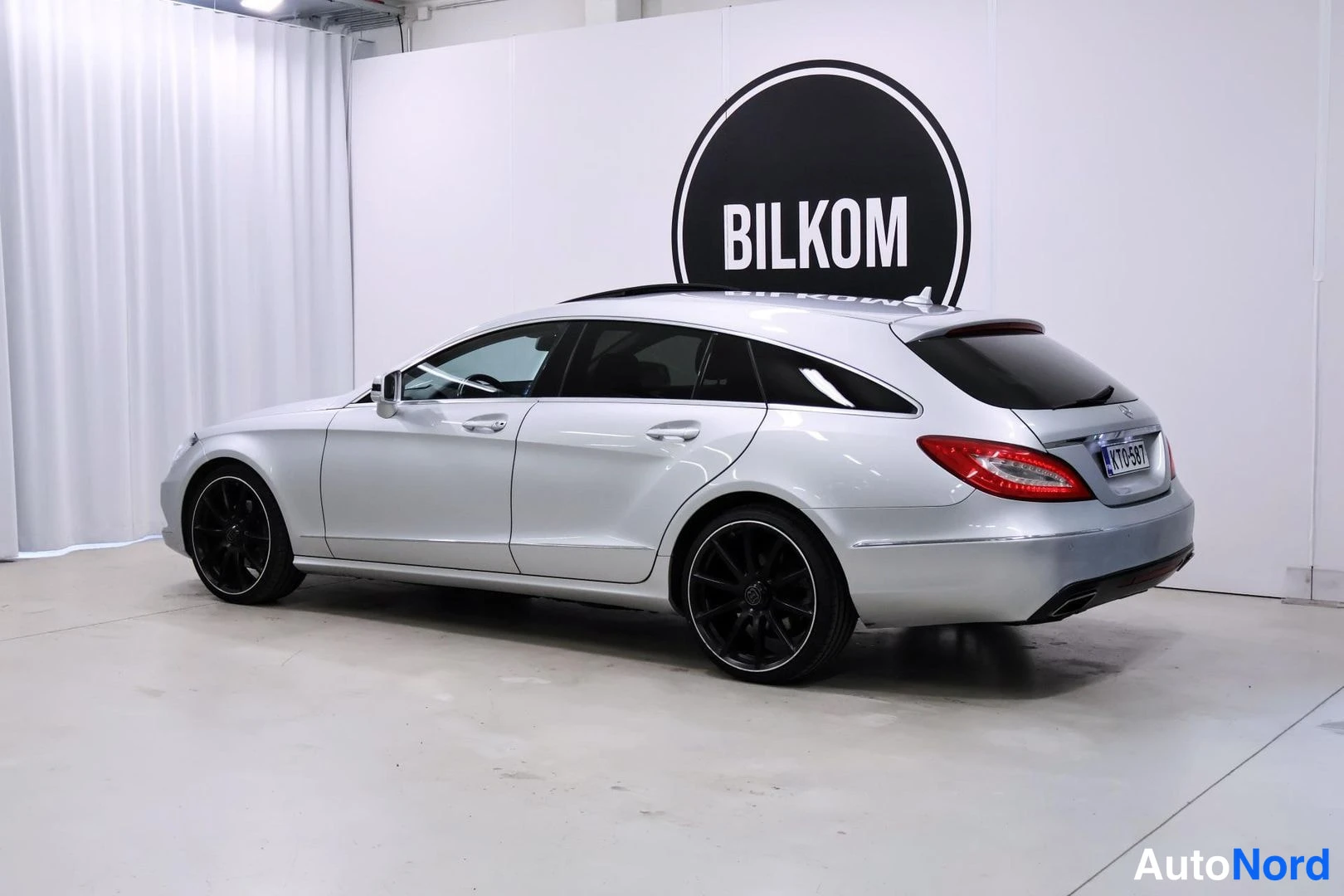 Takaviisto: Hopeinen Mercedes-Benz CLS -farmari takakolmasosasta kuvattuna oikealta puolelta, BILKOM-tunnuksen edessä.