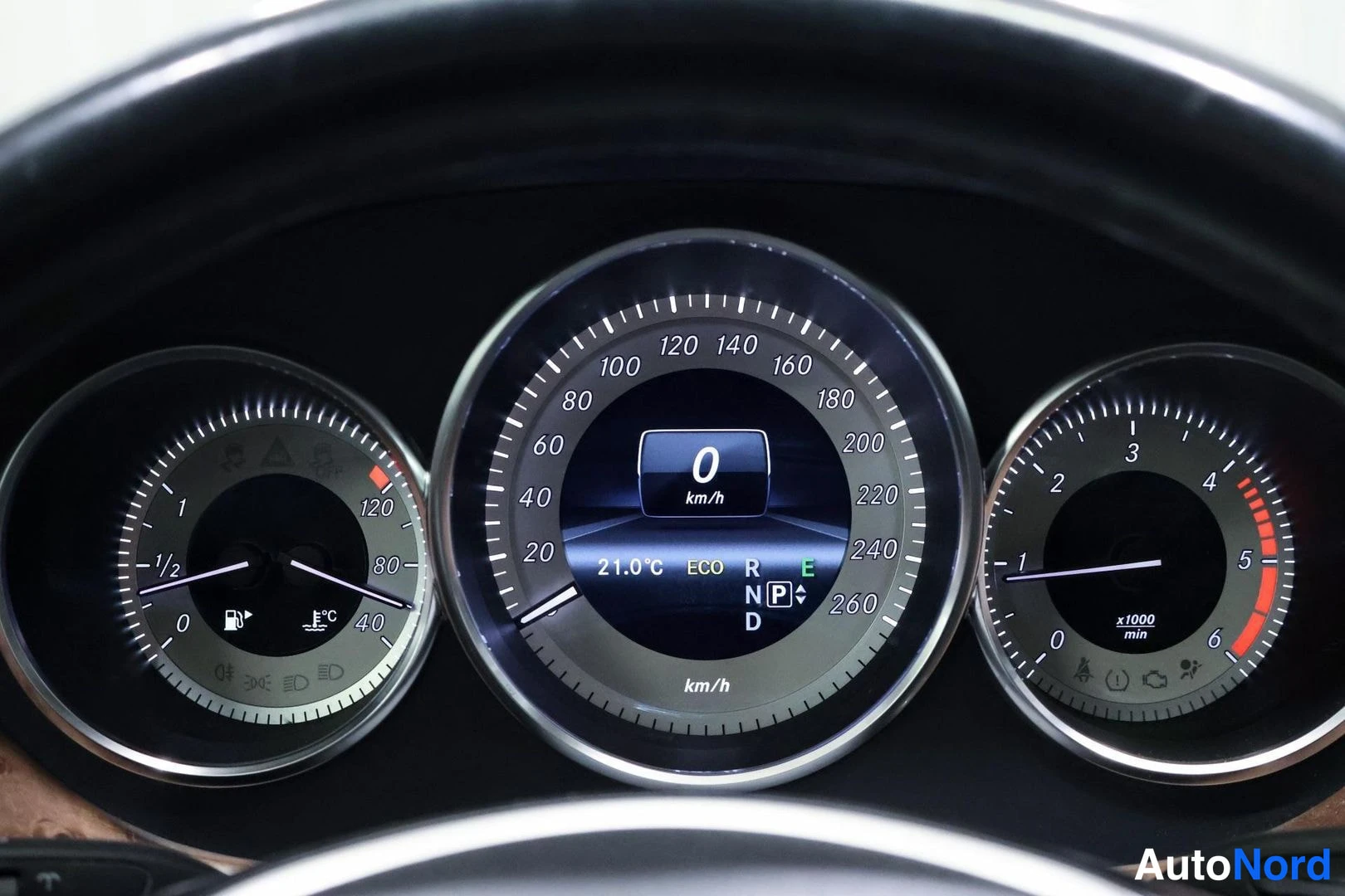 Muu: Mercedes-Benzin mittaristo: nopeusmittari näyttää 0 km/h, lämpötila 21,0 °C ja vaihde P; polttoaine- ja kierrosmittarit sivulla.