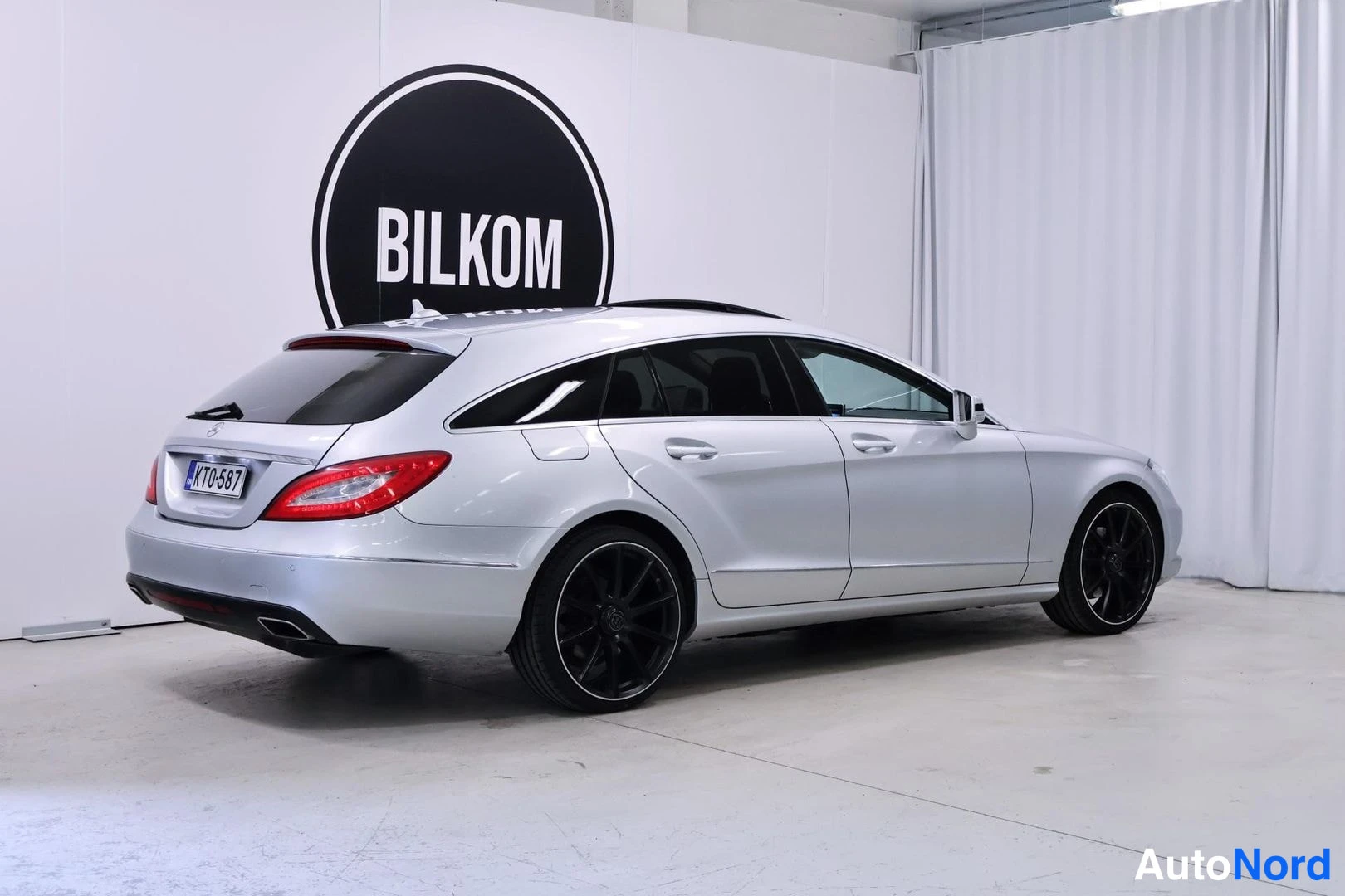 Takaviisto: Hopeinen Mercedes-Benz CLS -farmari takakolmasosasta kuvattuna vasemmalta puolelta, BILKOM-tunnuksen edessä.
