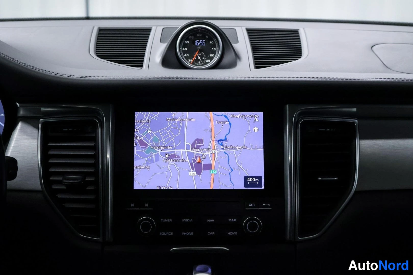 Muu: Kojeiston keskellä kosketusnäyttö, jolla näkyy navigointikartta Helsingin alueelta, yläotsikot TUNER, MEDIA, NAV, MAP, SOURCE, PHONE, CAR, HOME; kojelaudan yläo