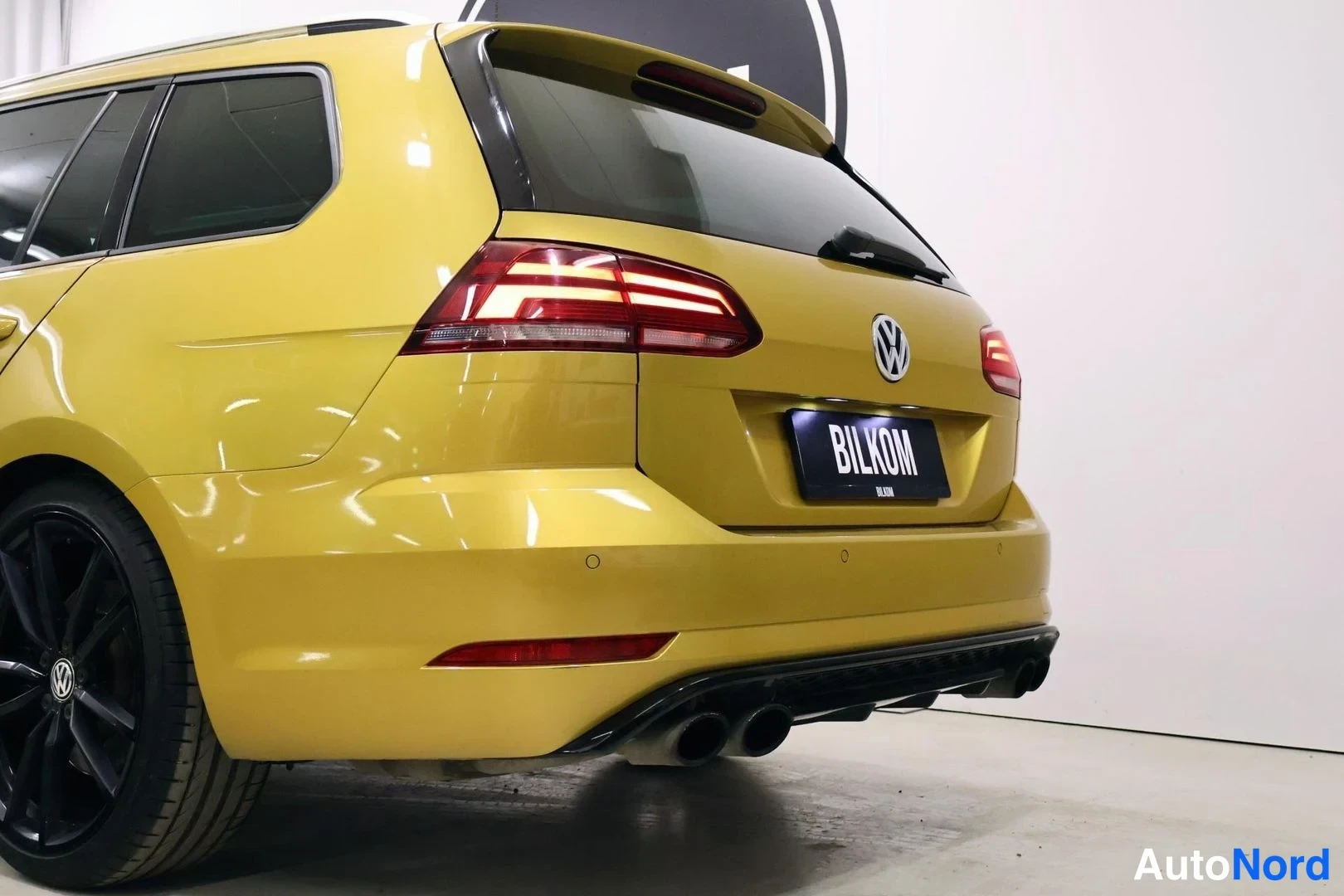 Takaviisto: Keltaisen Volkswagen Golf Variant -farmarin takaosa ja takakulma; peräovi, VW-merkki ja neljä pakoputkea näkyvät.