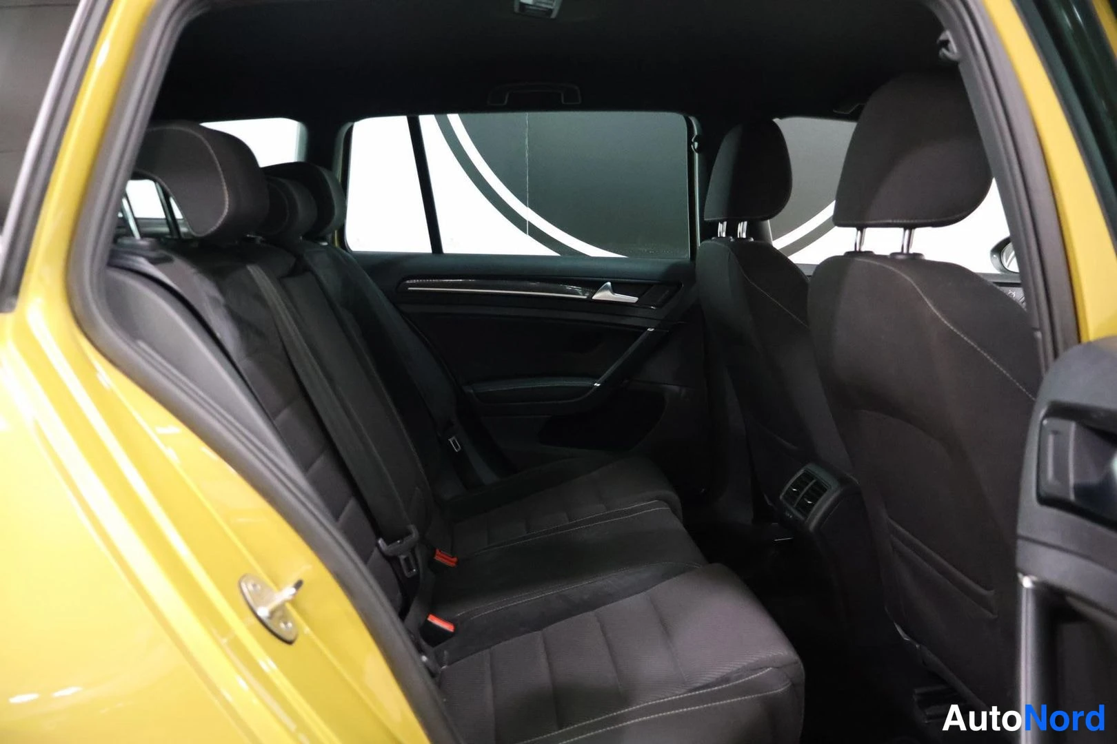 Takaistuimet: Rear cabin shot showing full width rear bench seat and window trim. Rear headrests and yellow exterior body visible on right side.