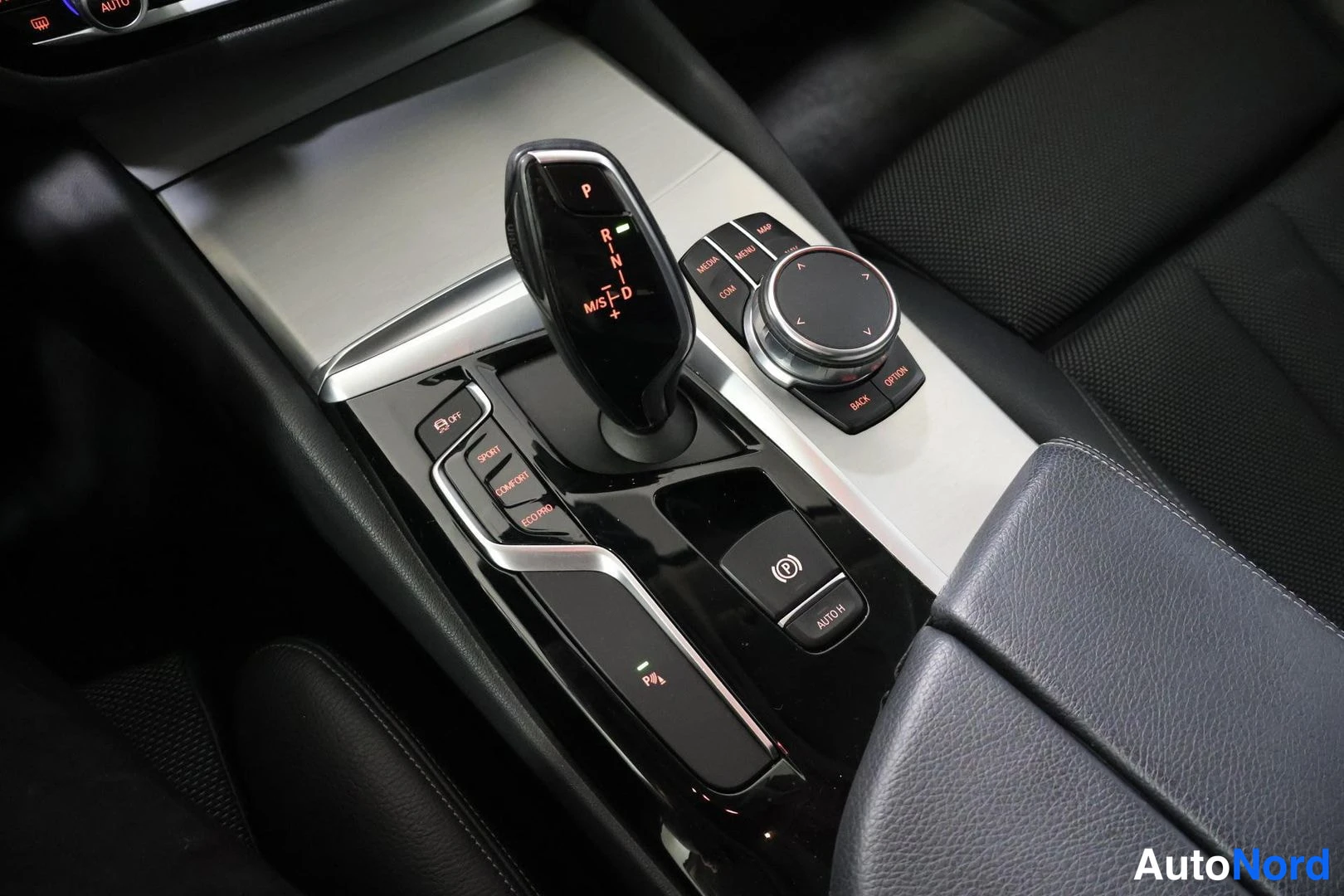 Muu: Center console showing automatic gear shifter with PRNDM/S+/−-display, iDrive rotary controller, and driving-mode buttons (SPORT, COMFORT, ECO PRO).