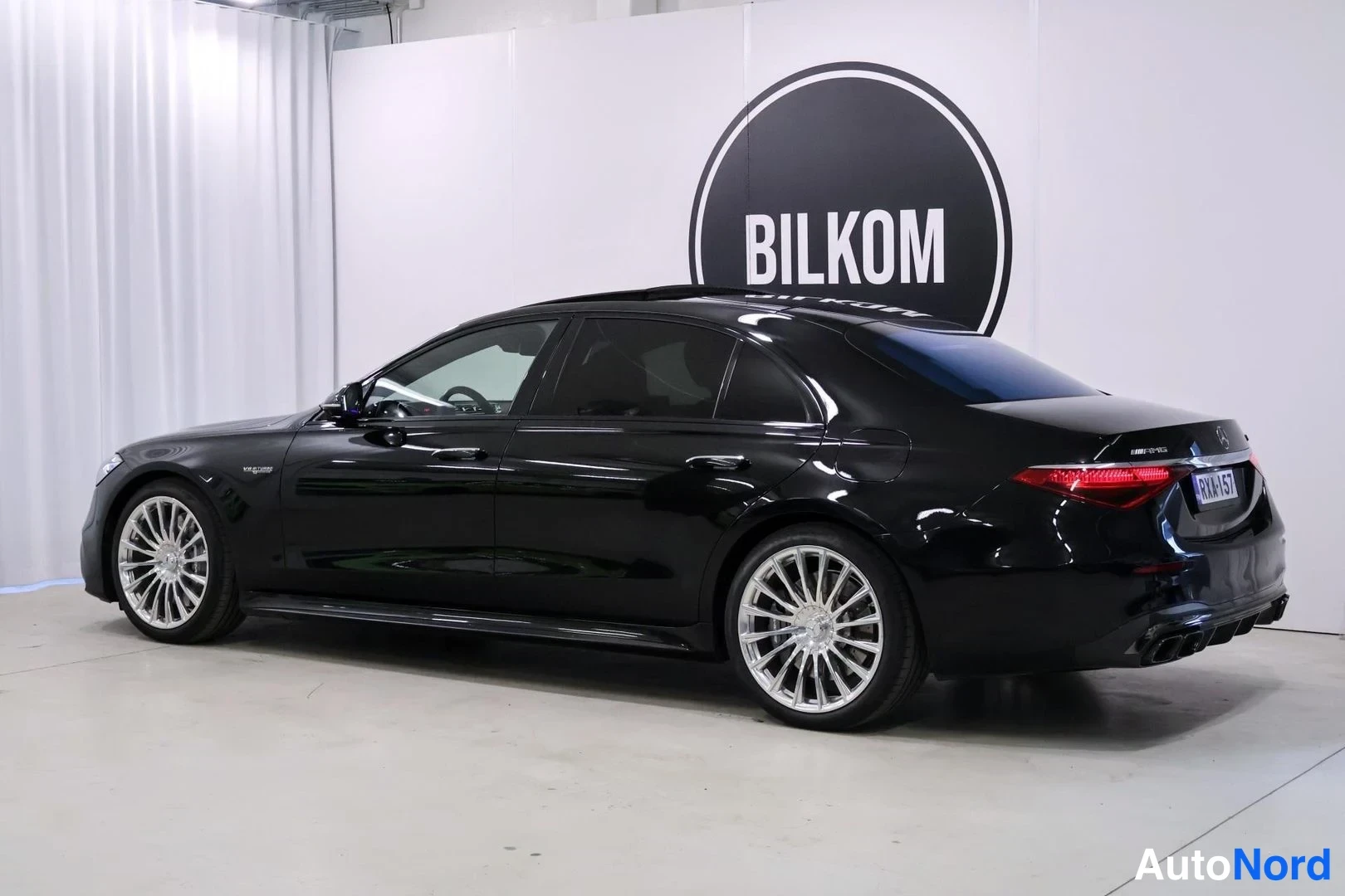 Takaviisto: Mustan Mercedes-Benz S 63 AMG -sedanin takaosa ja vasen kylki kolmivartalokuvassa sisätiloissa.