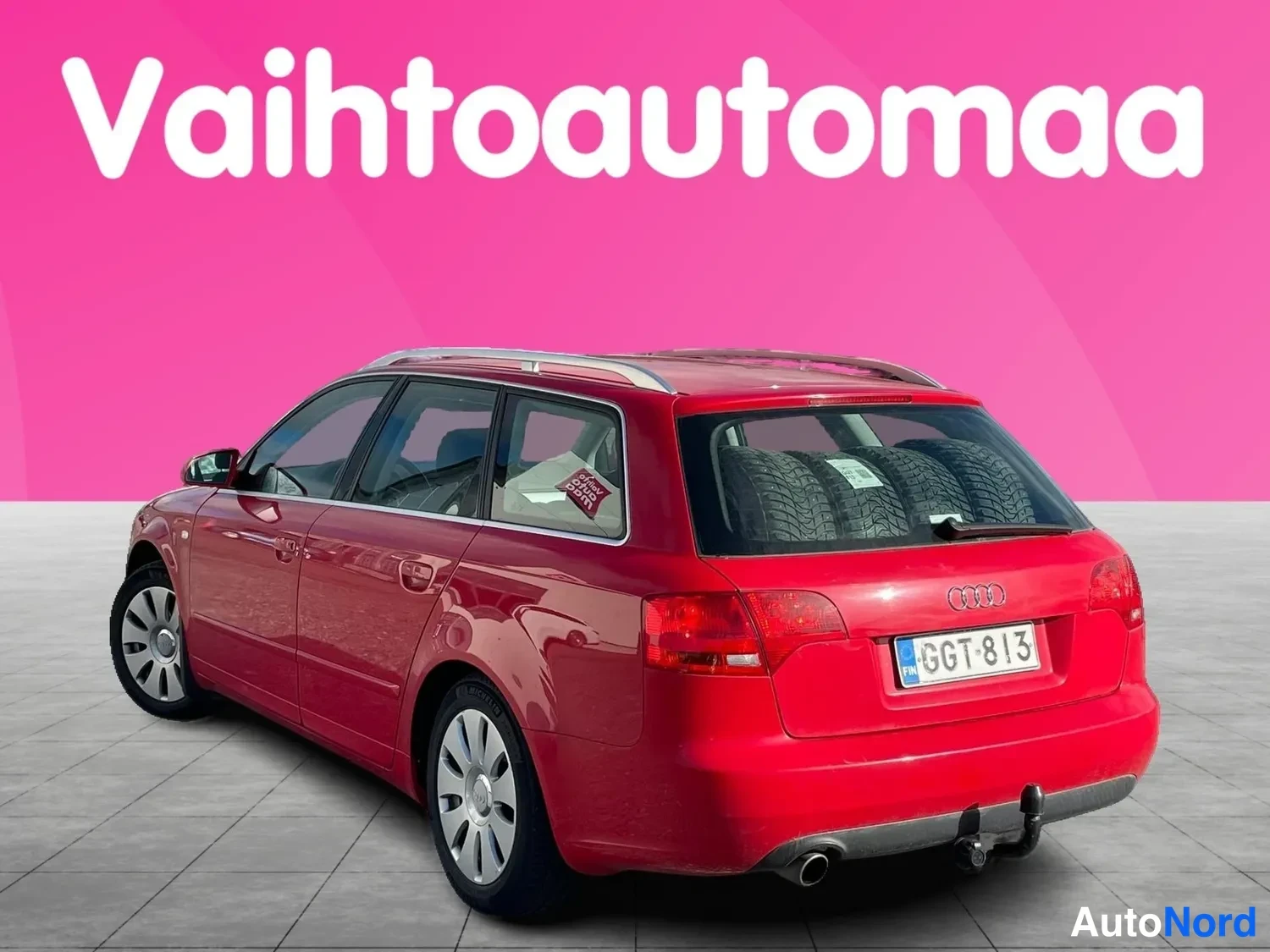 Takaviisto: Rear three-quarter view of the same red Audi station wagon showing the boot lid with spare tires inside, the tail lights, the exhaust pipe, the rear bumper and