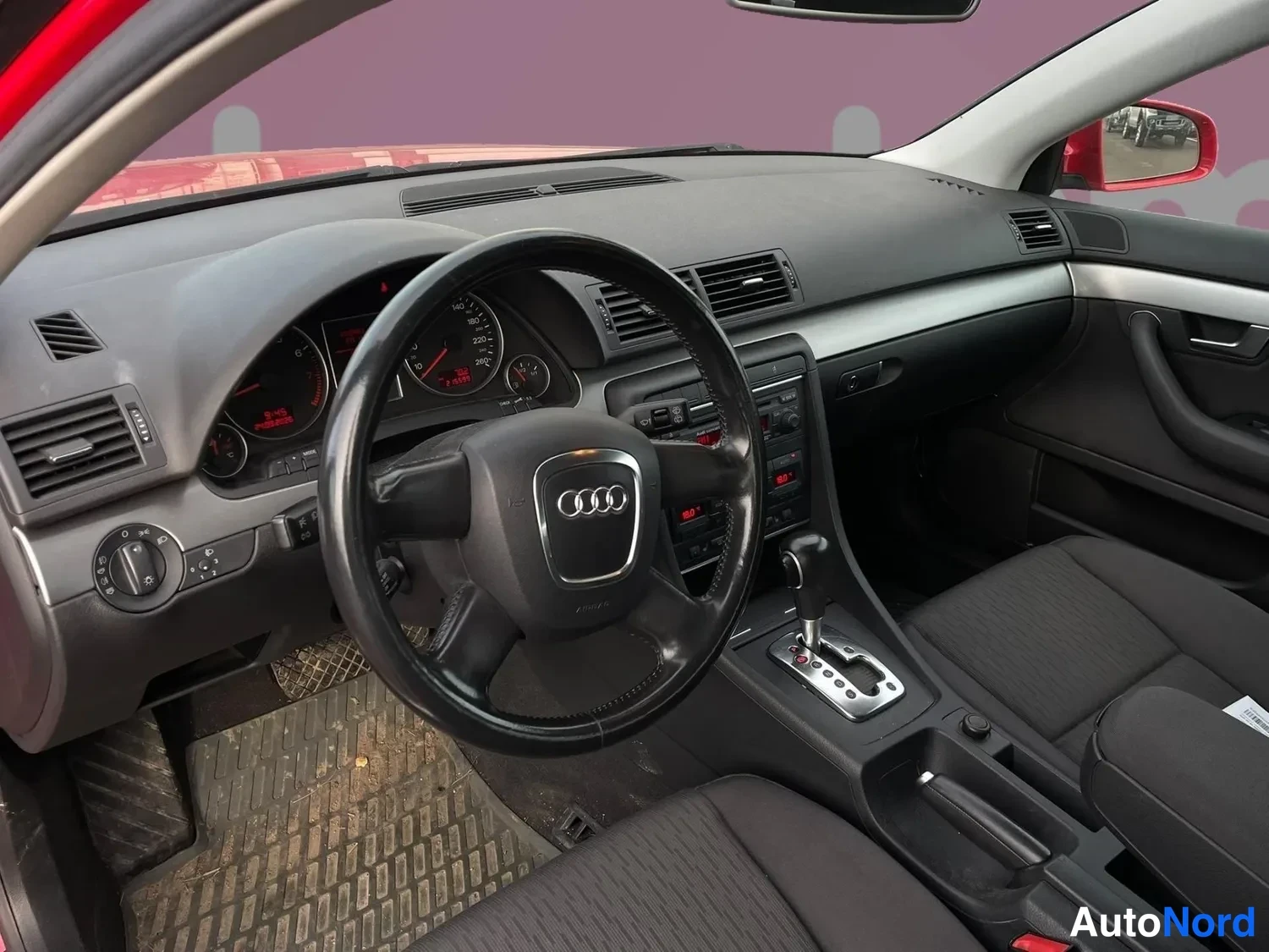 Ohjaamo: Interior shot of the driver's area showing the dashboard instrument cluster, the steering wheel, the automatic gear lever, the center console controls and the f