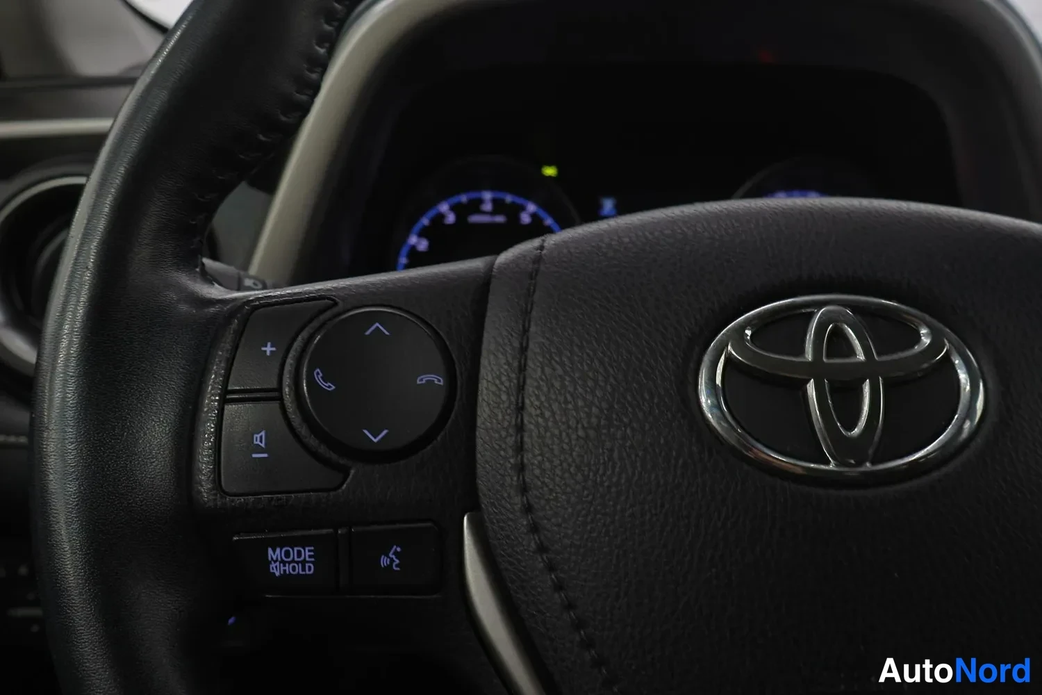 Muu: Ohjauspyörän lähikuva, Toyota-logolla ja monitoimipainikkeilla puheluun ja aantinevaimennukseen