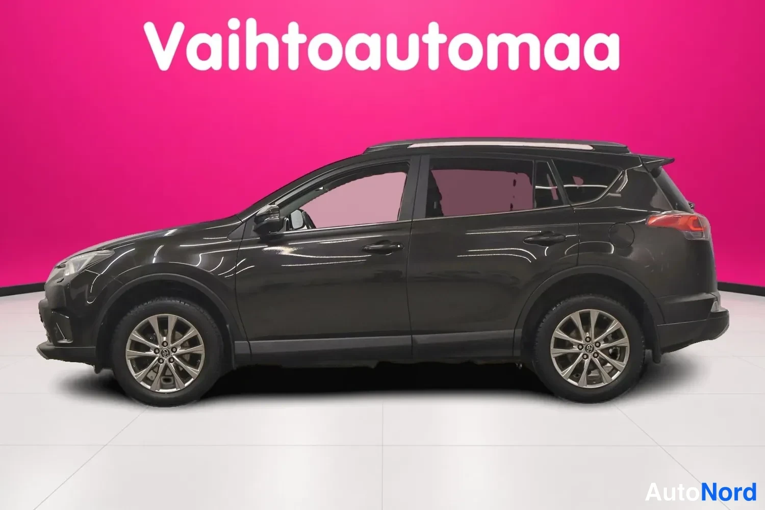 Sivulta: Mustanruskean Toyota RAV4:n takin täysi sivunäkymä, takavalojen reunat näkyvät oikealla reunalla vaaleanpunaisella taustalla.