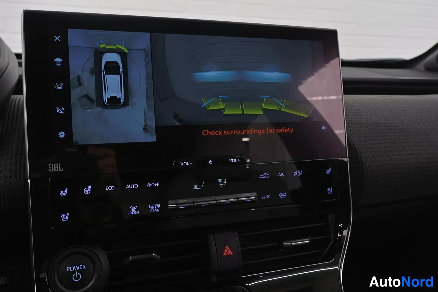 Muu: Keskikonsolan infotainment-näyttö näyttää 360-asteen kamera­kuvan auton ympäriltä ja teksti 'Check surroundings for safety', alla JBL-merkitty äänipaneeli ja il