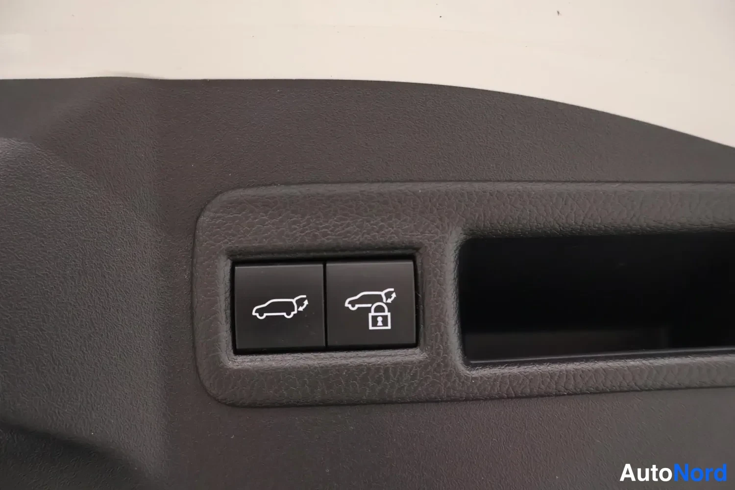 Takaa: Kaksi sähkötoimisen takaoven painiketta auton sisäpaneelissa, toisessa lukitussymboli.