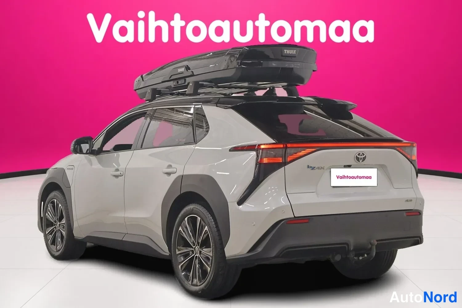 Takaviisto: Auton takaosa ja vasen sivu kolmen neljäsosan kulmasta; kattovarusteena musta Thule-kattoboksi, takavalojen poikittaispalkki jaToyota-merkki näkyvissä.