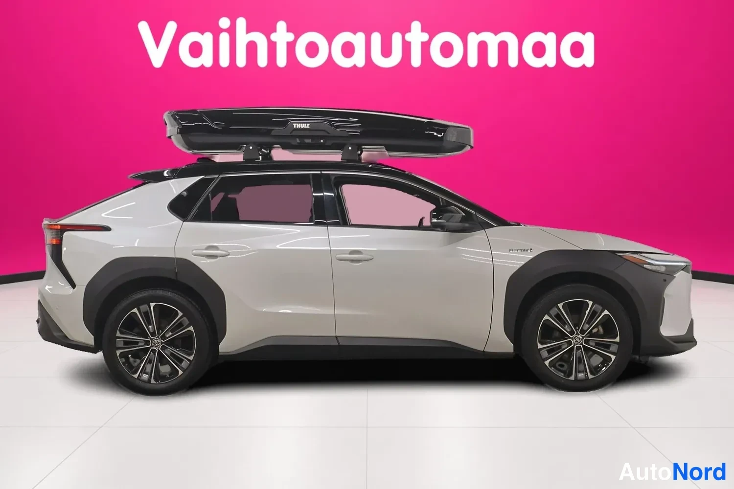 Sivulta: Auton vasen sivu sivuprofiilista; musta Thule-kattoboksi katolla ja mustat pyöränkaaren koristeet näkyvissä.