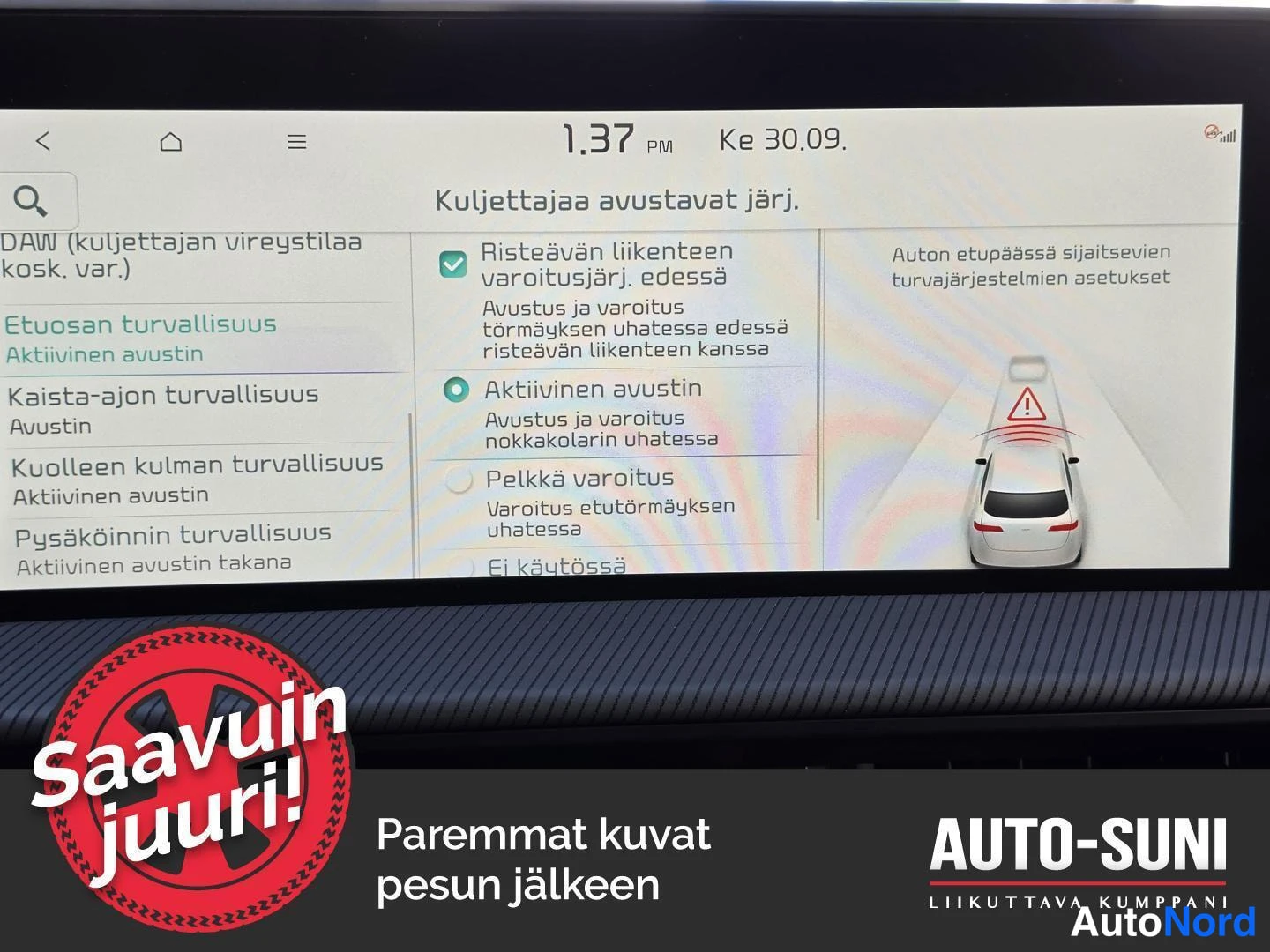 Etuviisto: Auton kojelaudan infotainment-näyttö, jossa on suomenkielinen valikko kuljettajaa avustavista järjestelmistä; valittuna Risteävän liikenteen varoitusjärj. edess