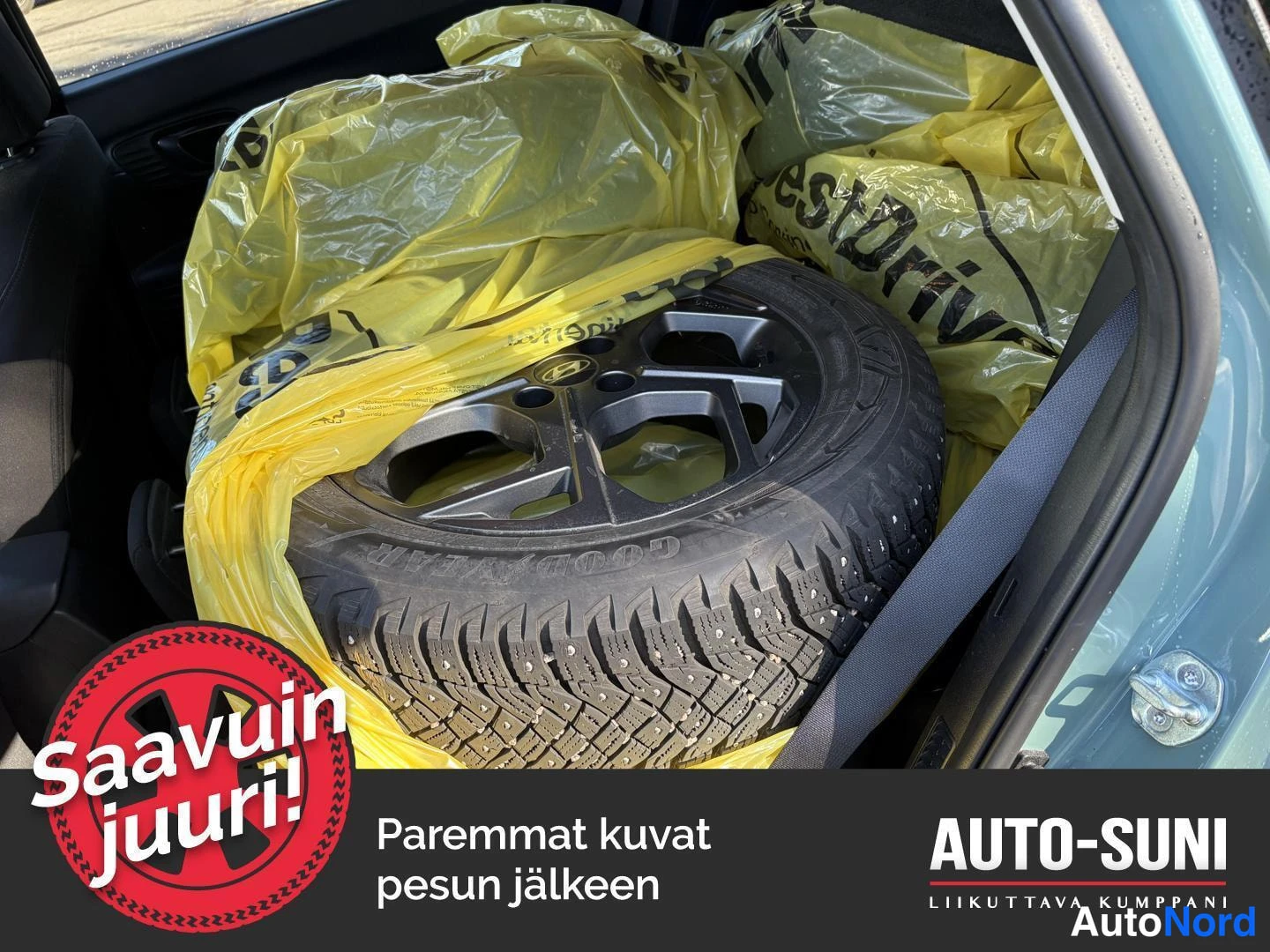 Yksityiskohta: Tavaratilassa vanteellinen talvirengas (Goodyear) keltaisissa muovipusseissa.