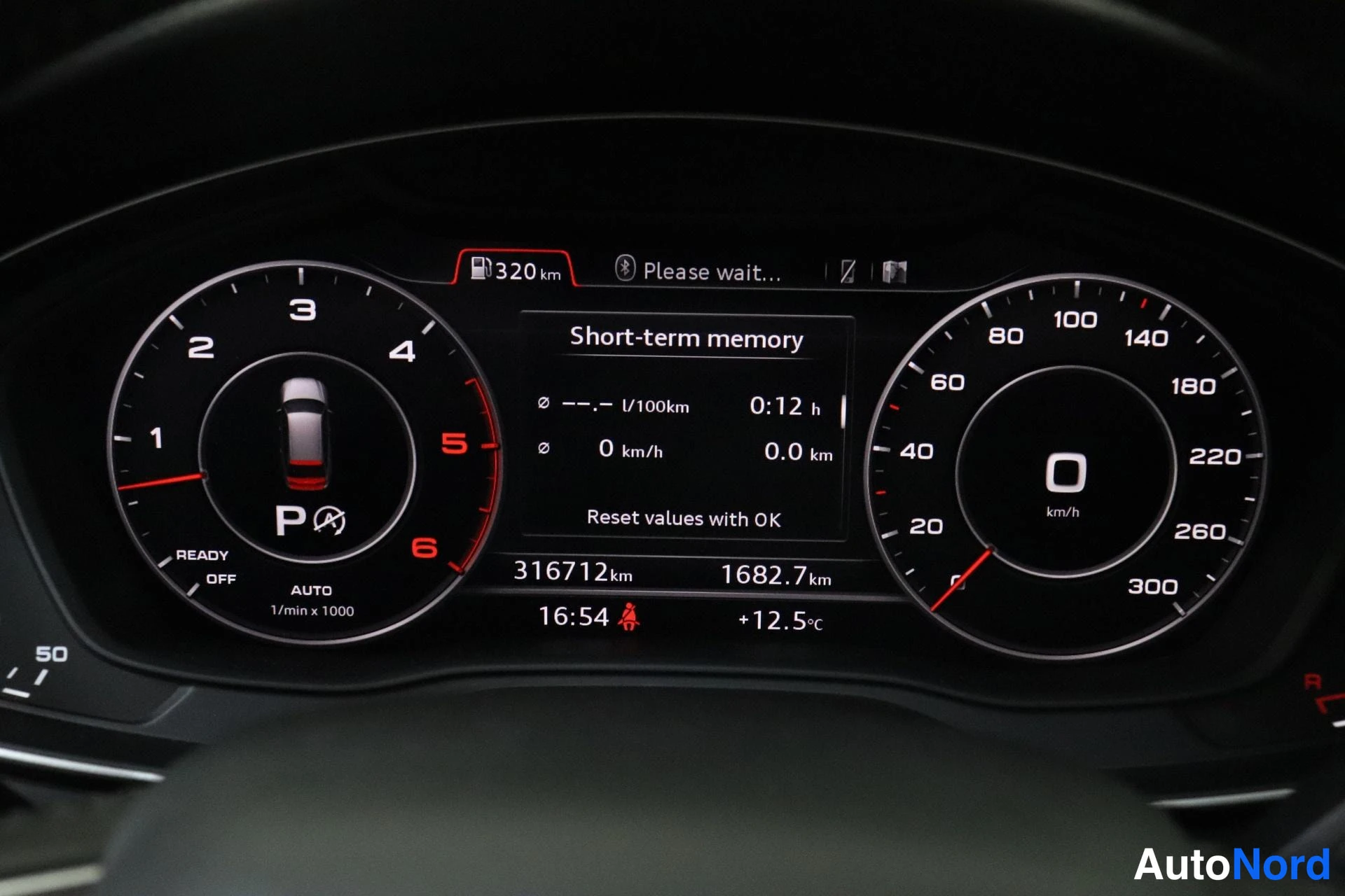 Yksityiskohta: Digitaalinen Audi-mittaristo: seisontavaihde P, nopeus 0 km/h, matkamittari 316712 km, päälle 1682,7 km, kellonaika 16:54, ulkolämpötila +12,5 °C, toimintasäde