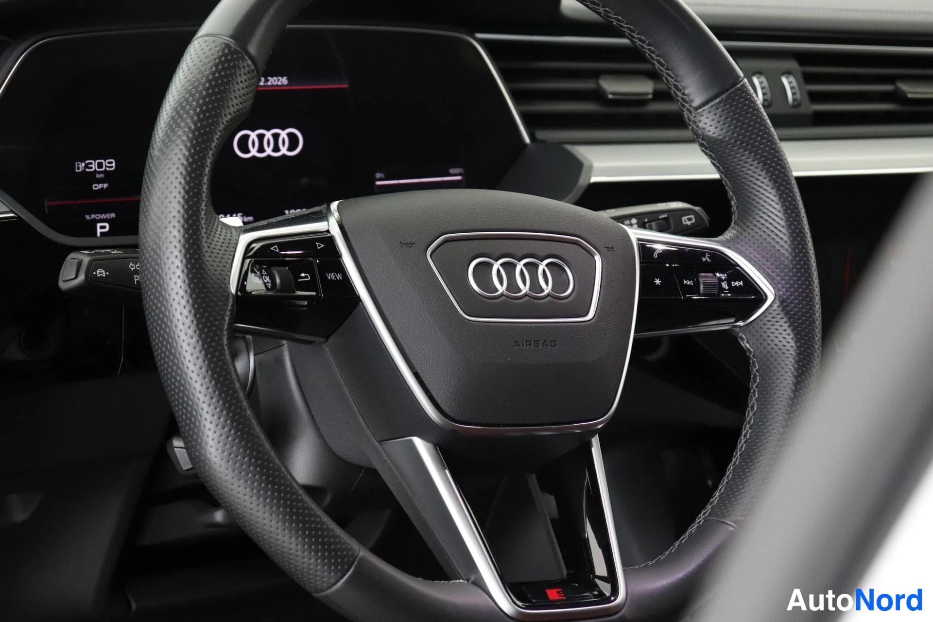 Yksityiskohta: Audi-merkin ohjauspyörä ja digitaalinen mittaristo, jonka näytöllä lukee 309 ja P.