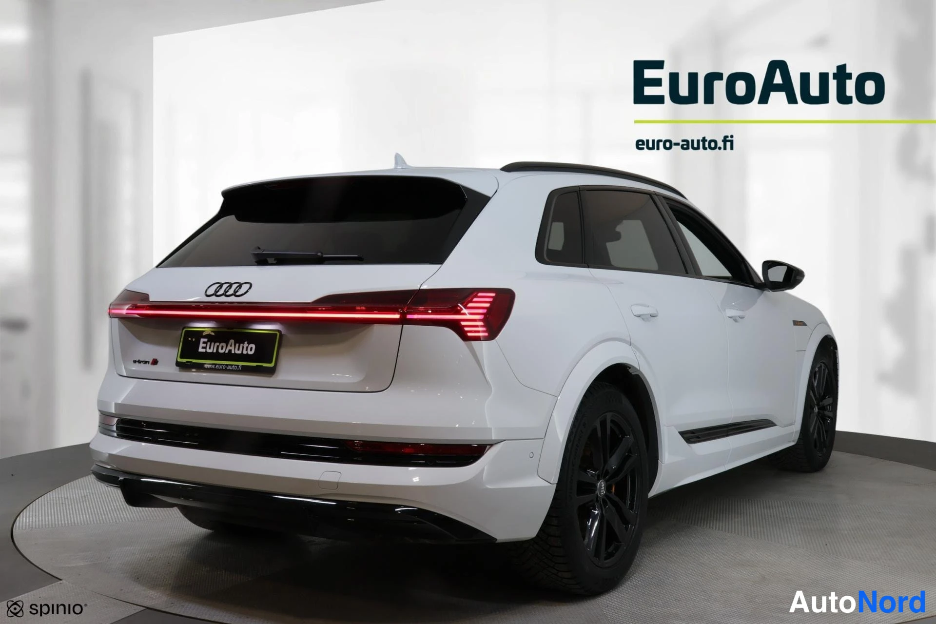 Takaviisto: Valkoinen Audi e-tron S takaa oikealta kuvattuna: punainen poikittainen takavalo, mustat kevytmetallivanteet ja auton oikea kylki näkyvissä.
