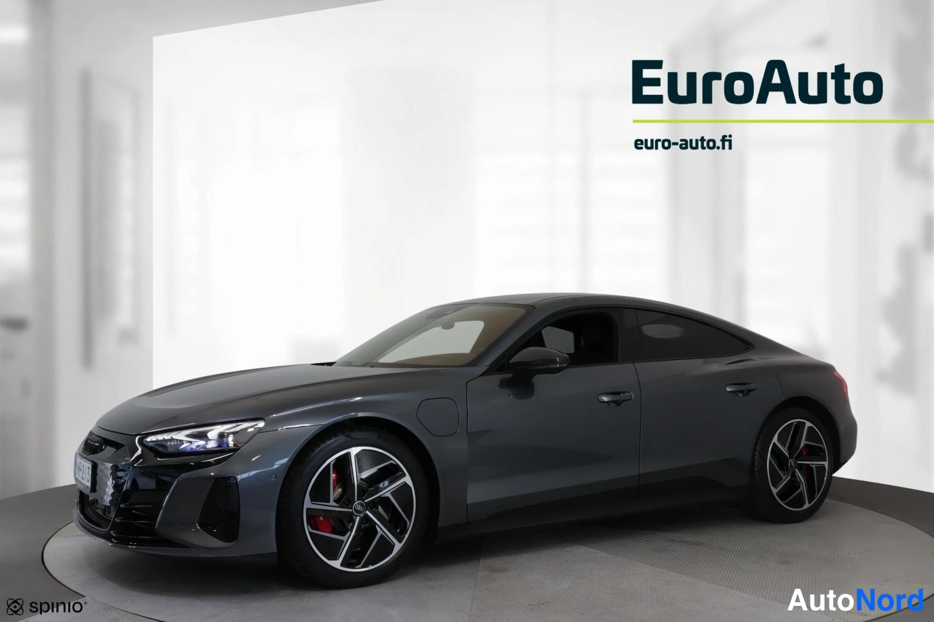 Etuviisto, nokka vasemmalle: Audi e-tron GT -urheilusedän etukulma, tummanharmaa kori ja moniosaiset kevytmetallivanteet studiovalaistuksessa.