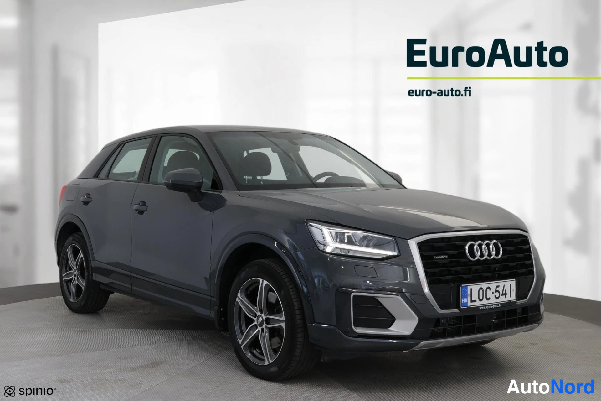 Etuviisto, nokka vasemmalle: Viisivärinen harmaa Audi Q2 nelikulma etu- ja oikealta puolelta. Etusäleikkö, Audi-renkaat, LED-kiristimet, takavalojen yläpuolella oleva 'quattro'-mai