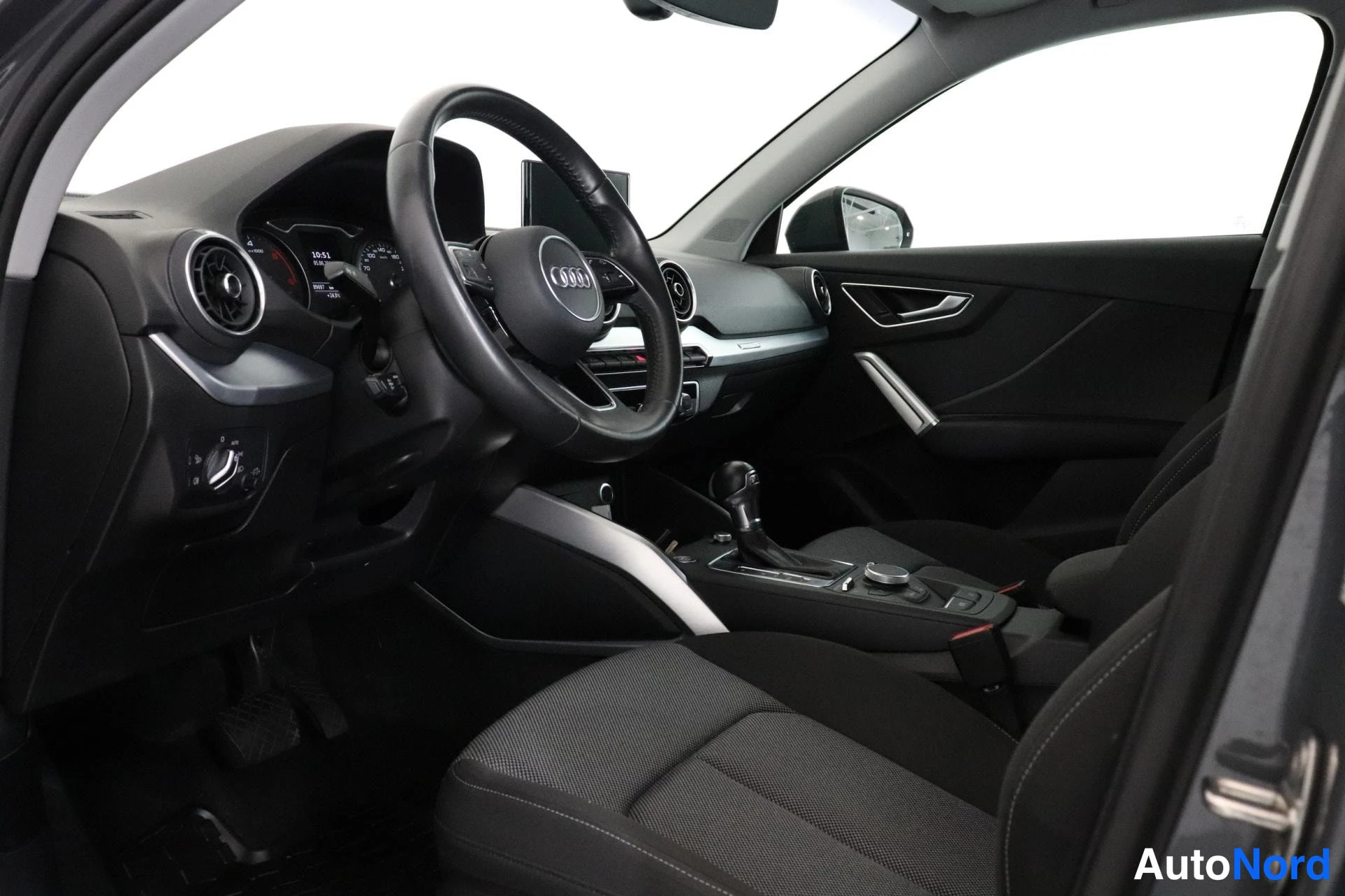 Etuistuimet: The interior cabin view showing the driver's seat, multifunction steering wheel, and center console gear shifter.