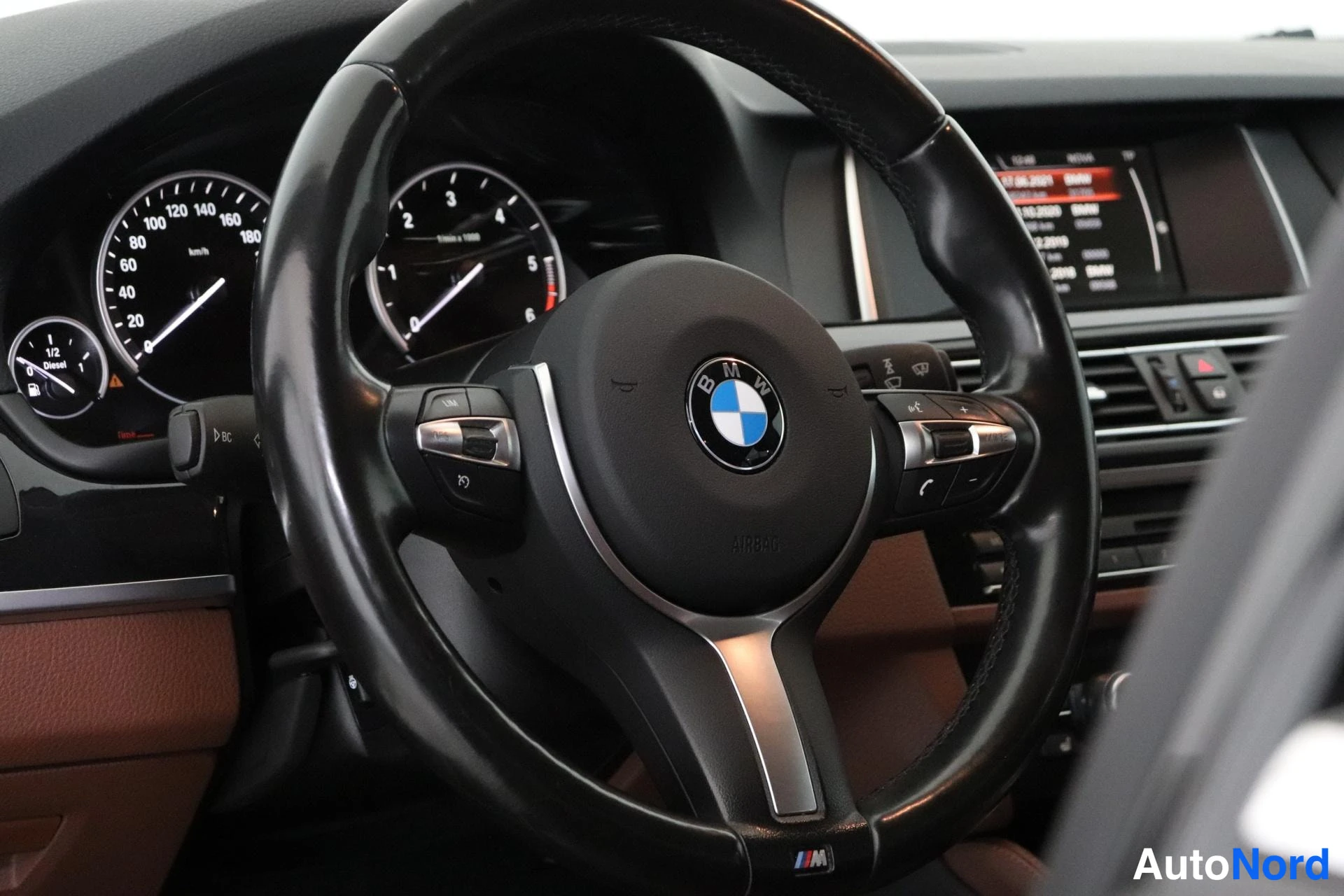 Muu: Lähikuva BMW-ohjauspyörästä ja mittaristosta; nopeusmittari, kierroslukumittari ja polttoainemittari näkyvät.