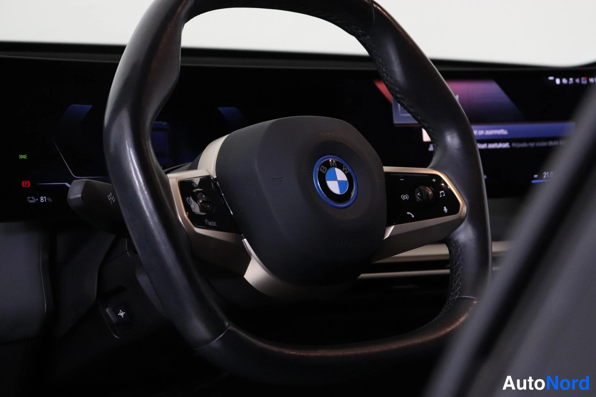 Muu: Ohjauspyörä BMW-tunnuksella ja monitoiminapeilla, taustalla digitaalinen mittaristo ja infotainment-näyttö.